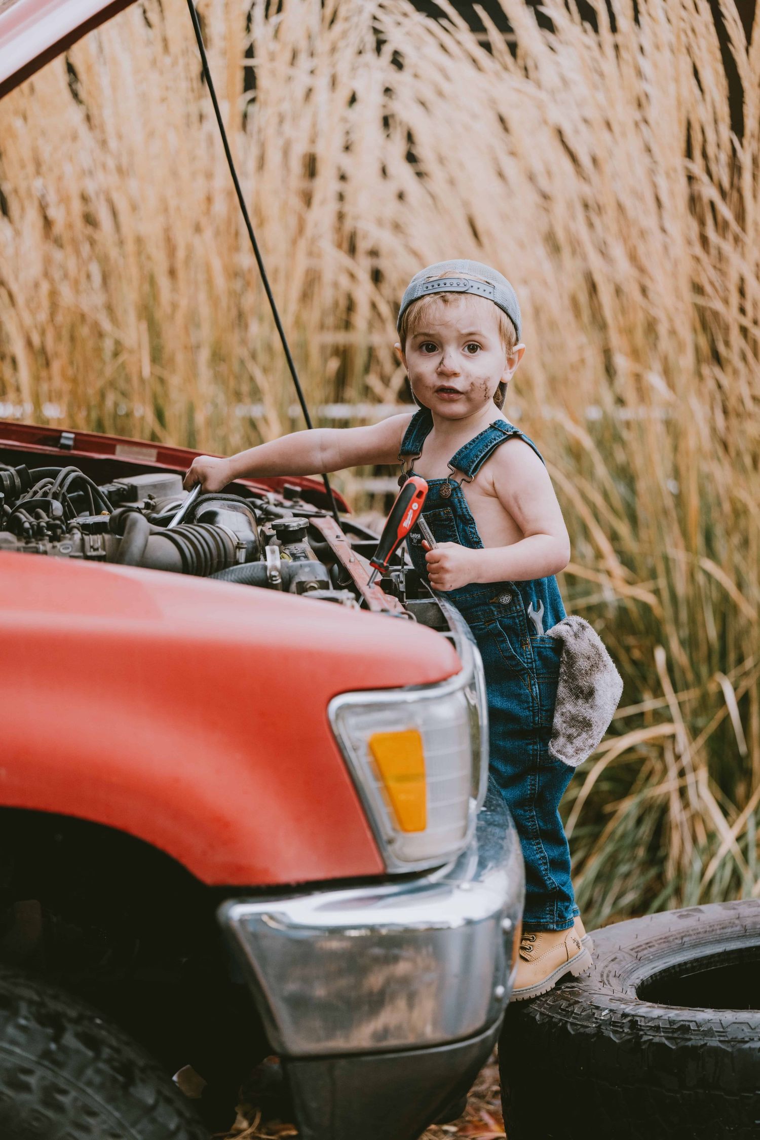 A candid photo of a two year old working on a classic truck.