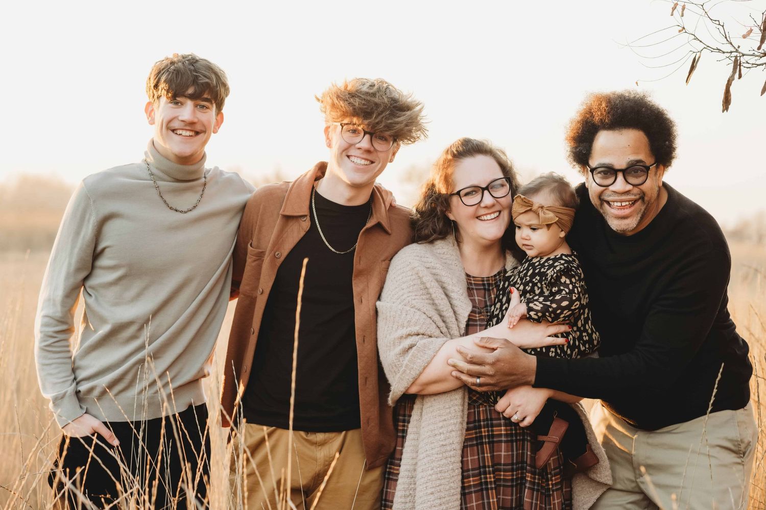 A family of five embracing each other during golden hour.