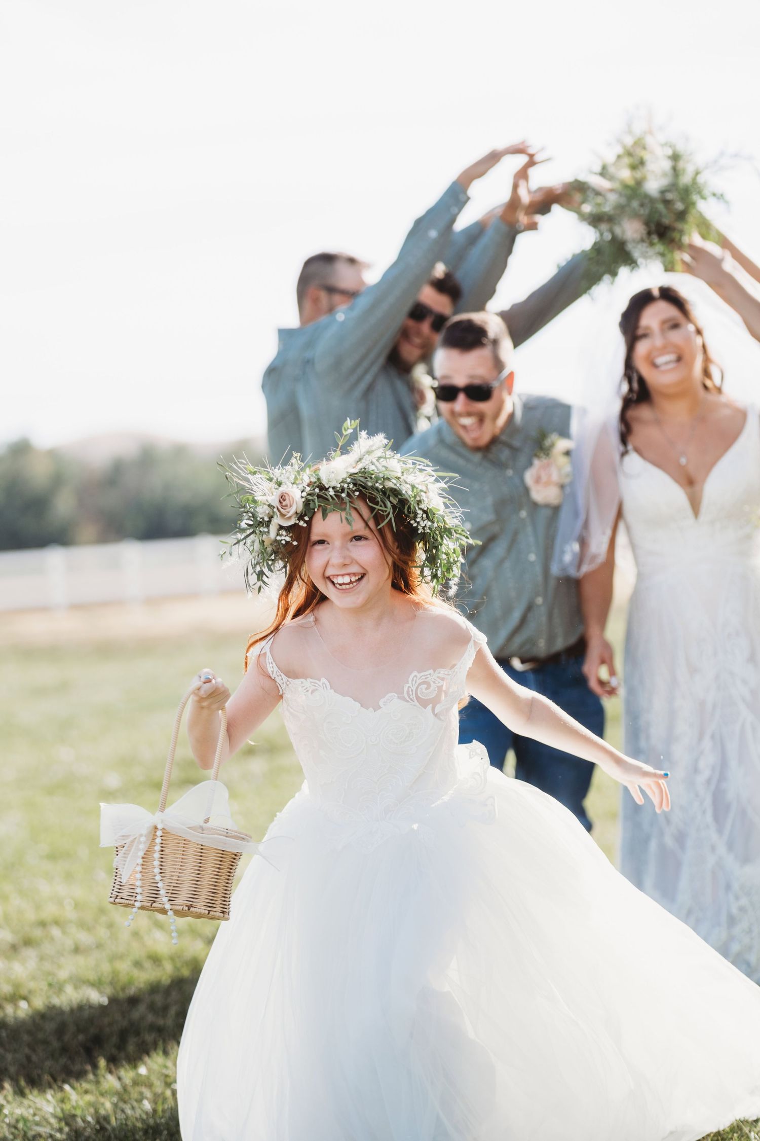 A flower girl running with the bride and groom following behind her.