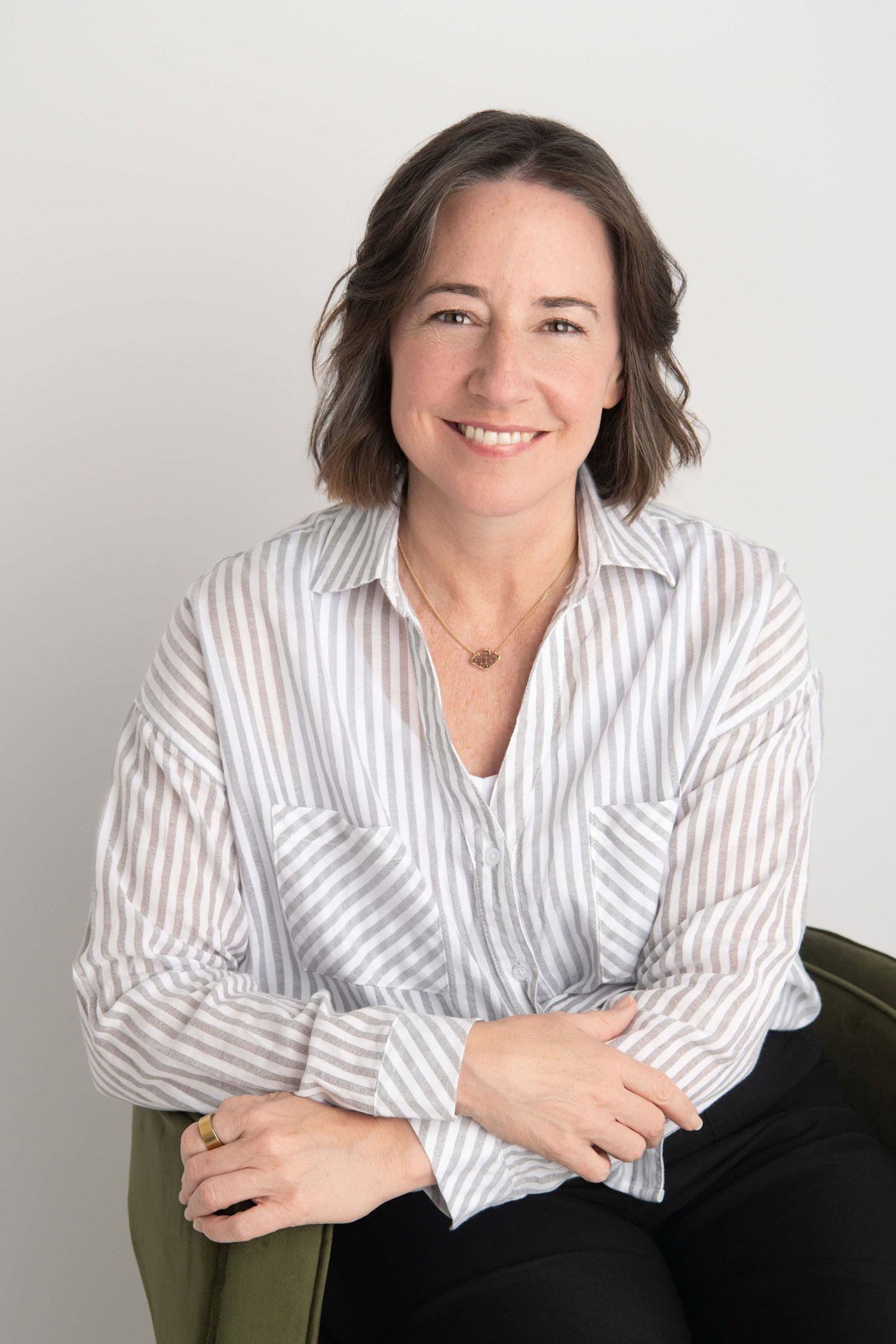 A headshot of a woman sitting in a chair on a white backdrop by a Walla Walla headshot photographer.
