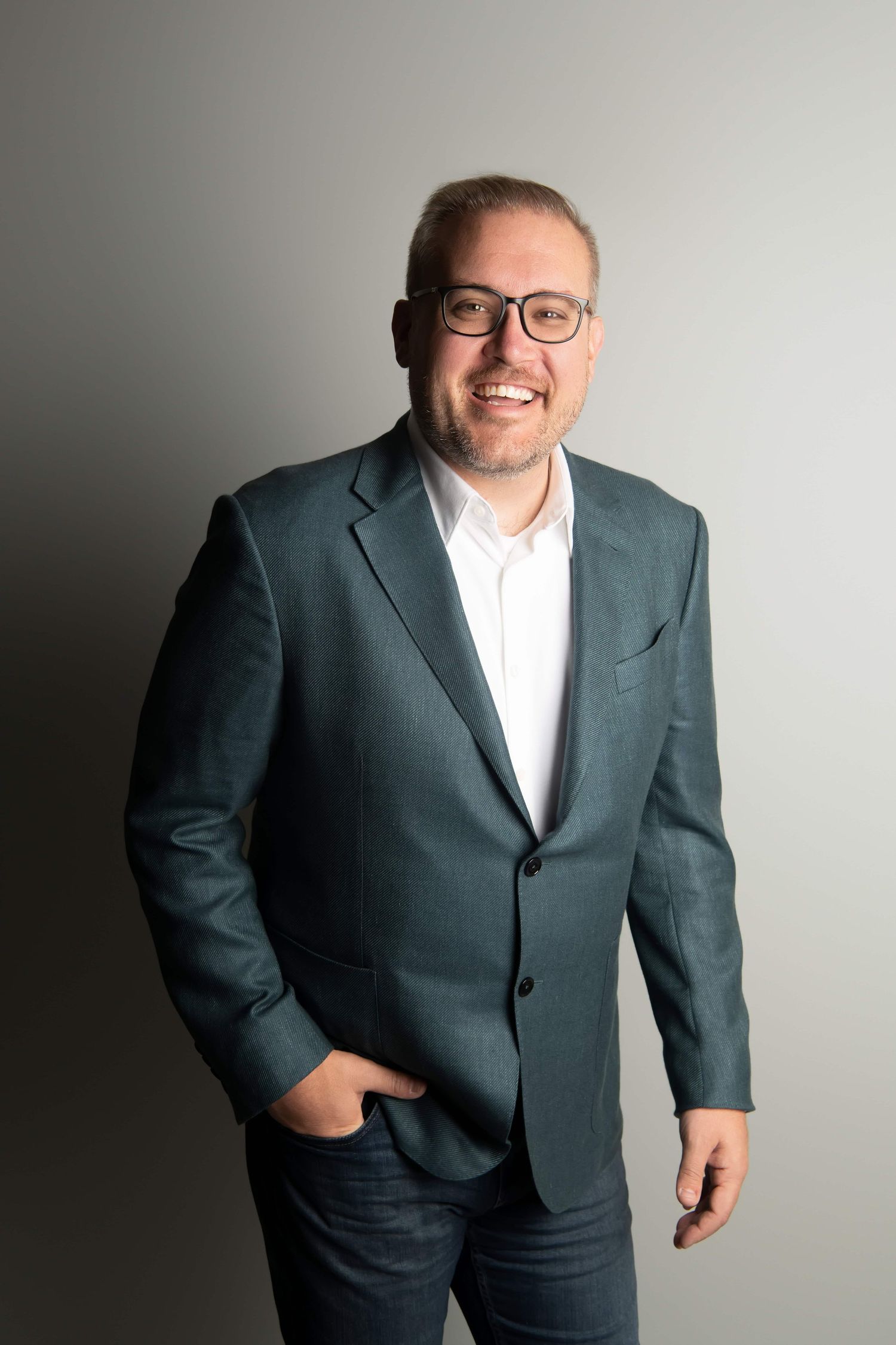 A classic headshot of a man in a suit on a gray backdrop in studio.
