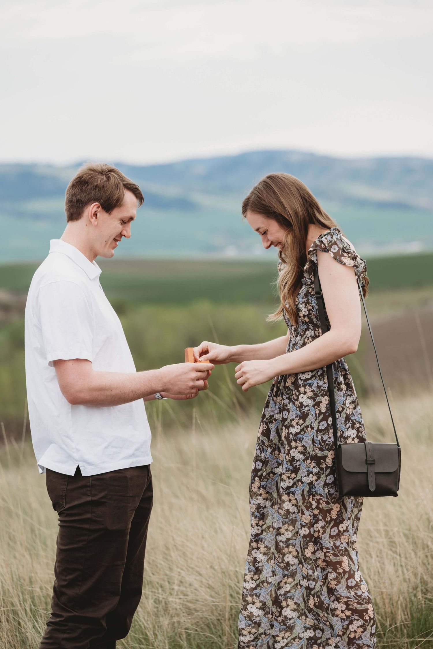 A woman looking at the ring that her boyfriend just proposed with, with an excited expression on her face.