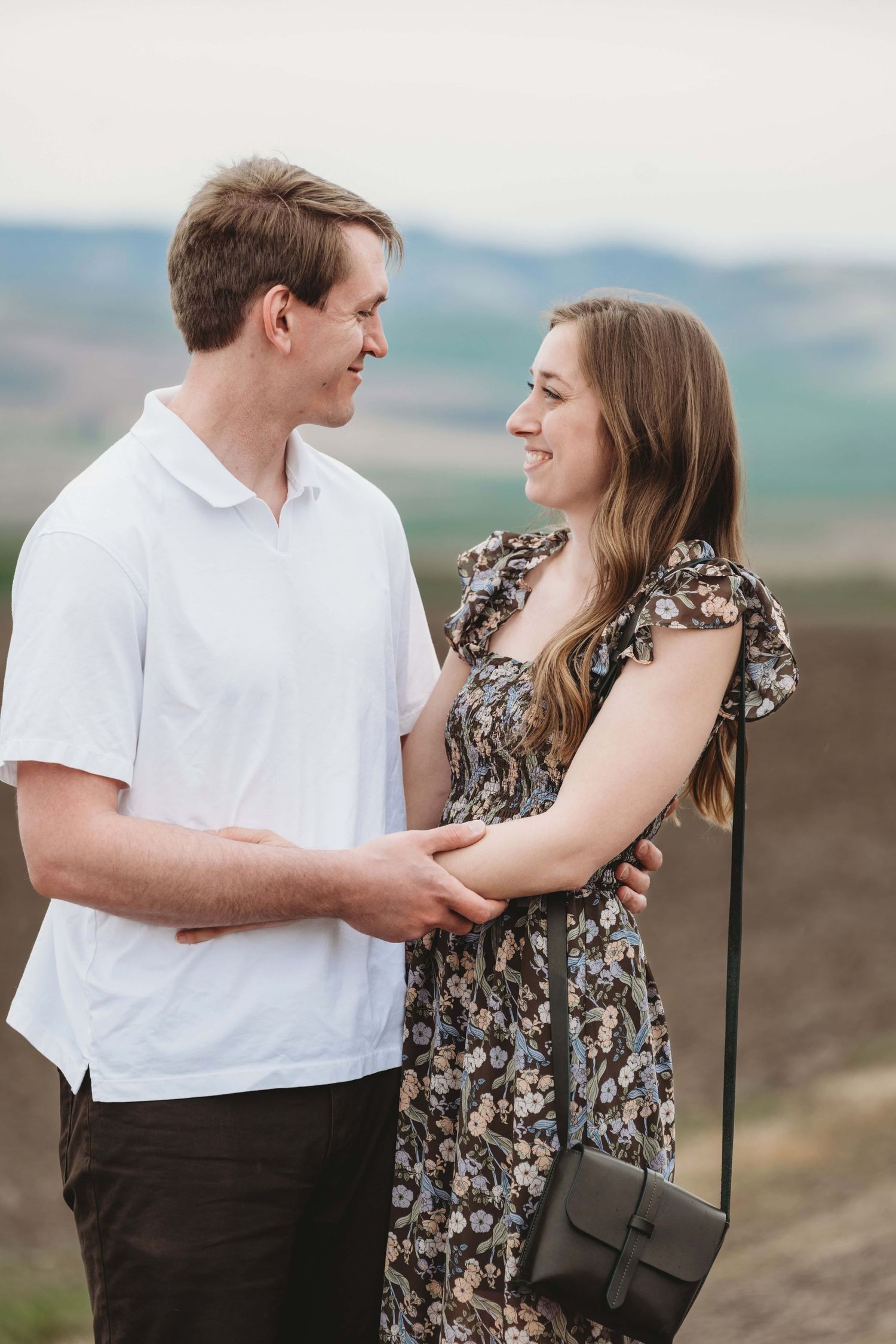 A couple looking at each other, smiling on a cool spring day.