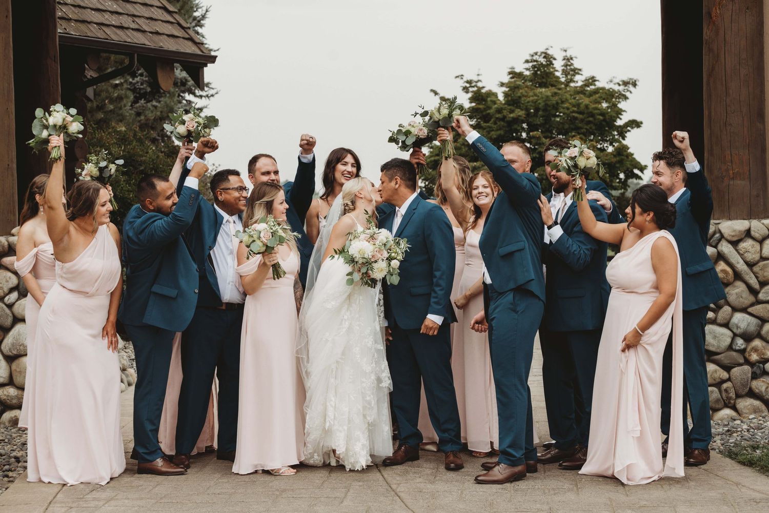 A bridal party cheering on the bride and groom as they share a kiss before their wedding in Walla Walla.