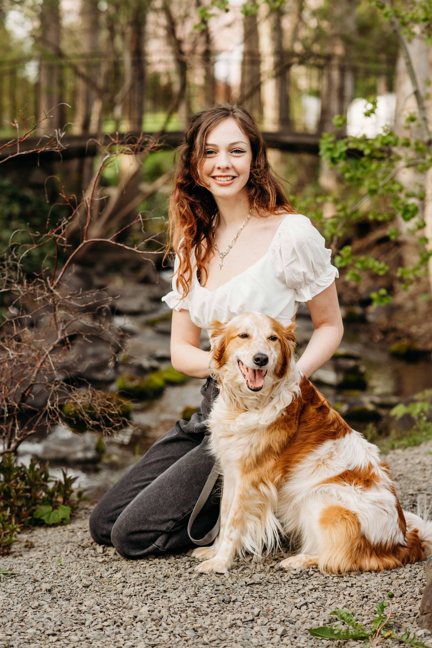 A senior sitting in front of a creek with her dog, captured by a Walla Walla photographer.