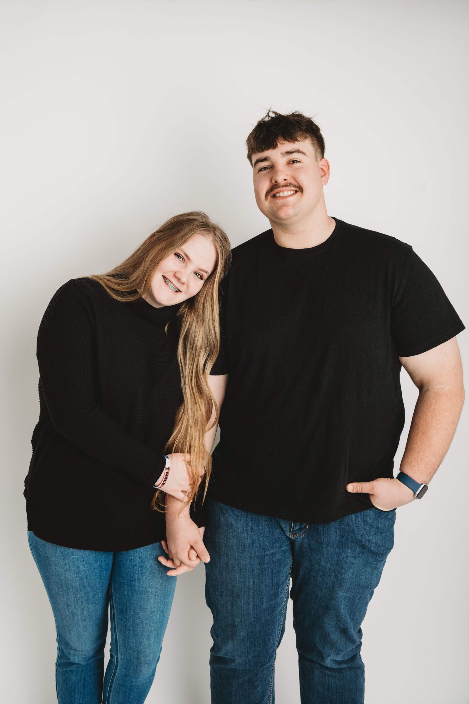 Studio portrait of a young couple standing side by side, captured by a Walla Walla couples photographer on a light neutral backdrop.