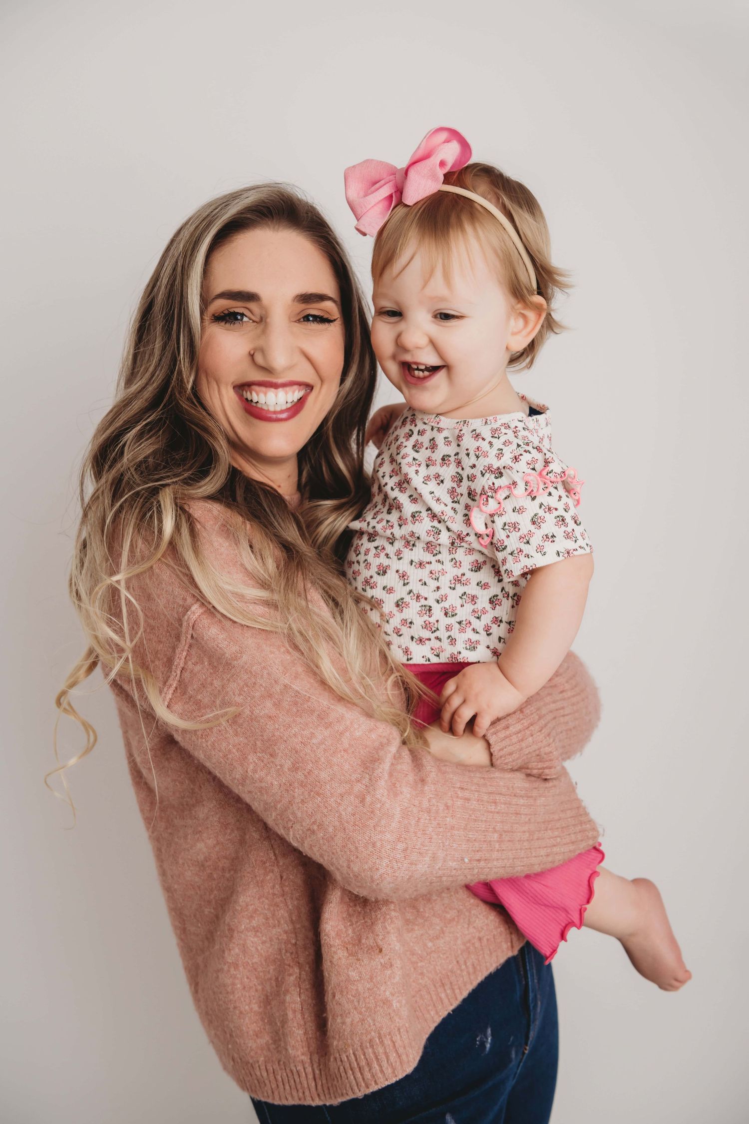 A studio portrait of a mom and her baby laughing.