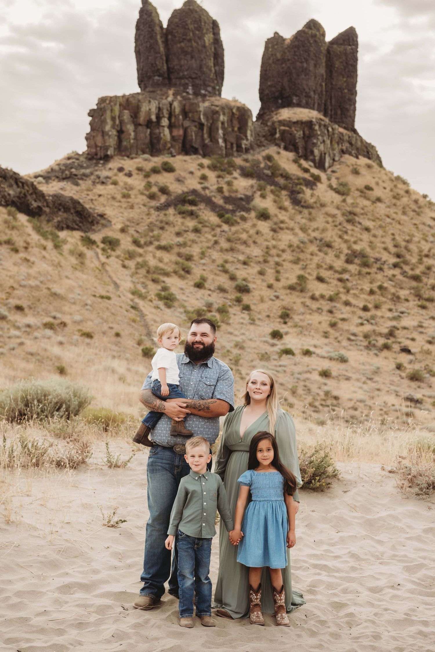 Family photography in Walla Walla featuring parents and children posing together in front of a desert rock landscape.