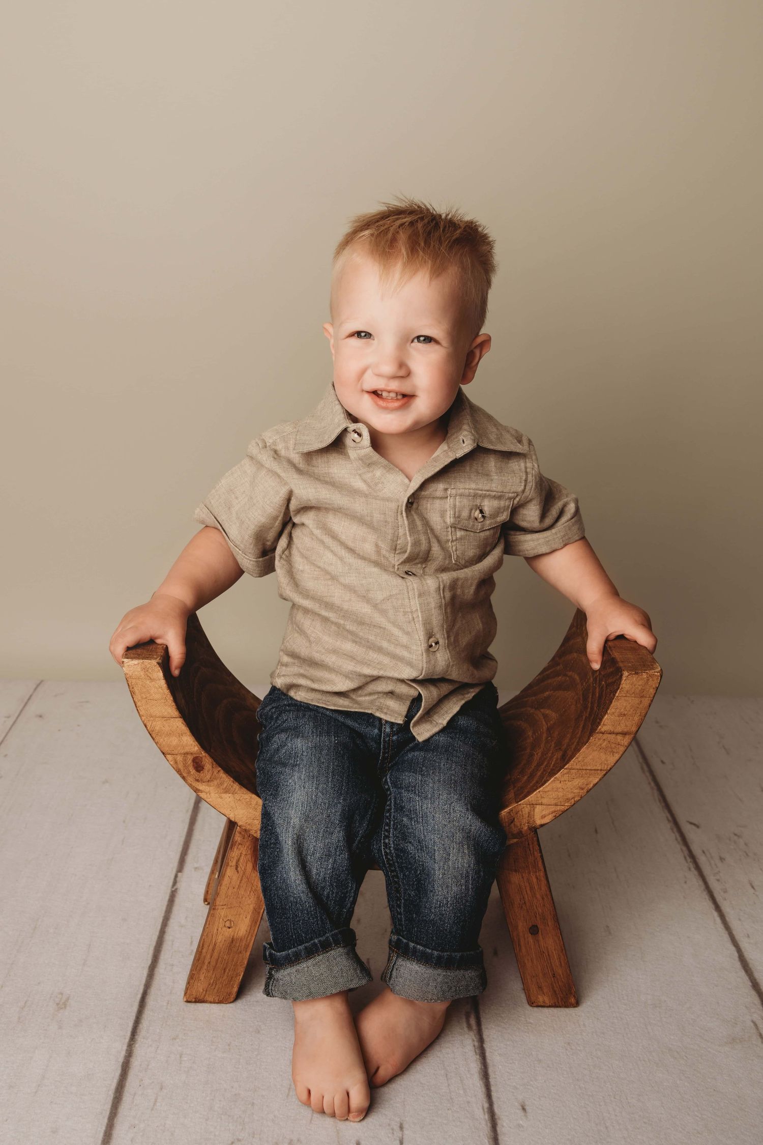 A Walla Walla photographer captures a boy sitting on a wooden stool and smiling.