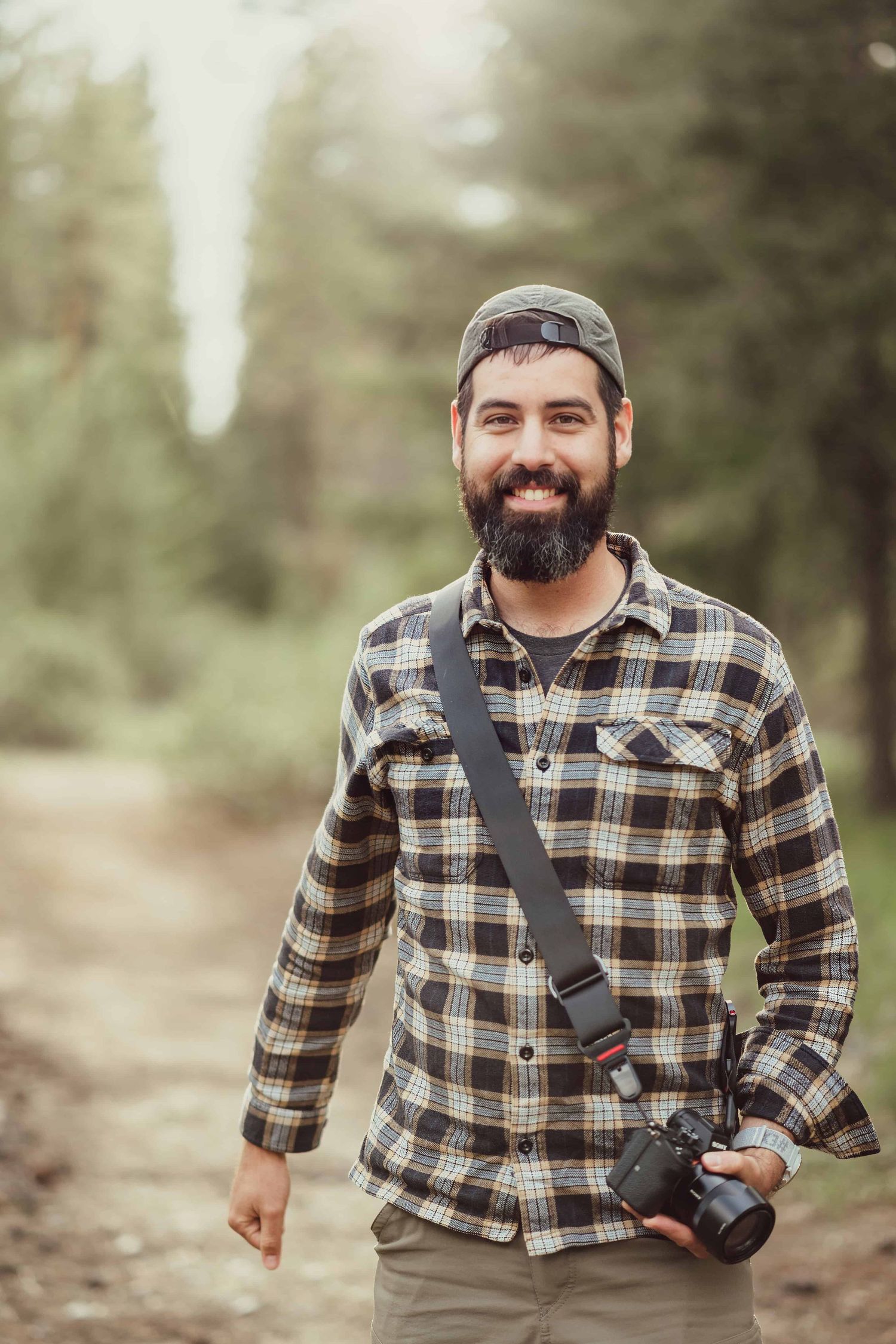 Headshot portrait of a man holding a camera on a wooded path, taken by a Walla Walla photographer.