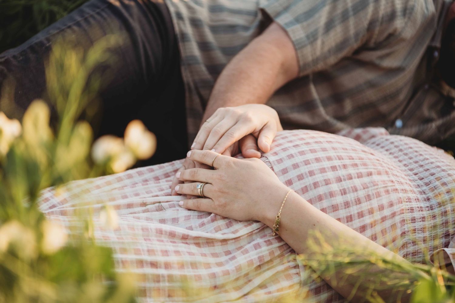 A close up of a couple holding hands on top of a baby bump.