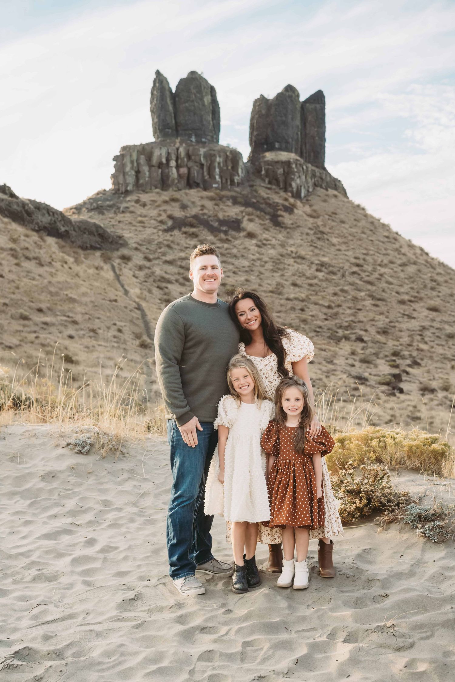 A family of four standing in front of a rock formation.