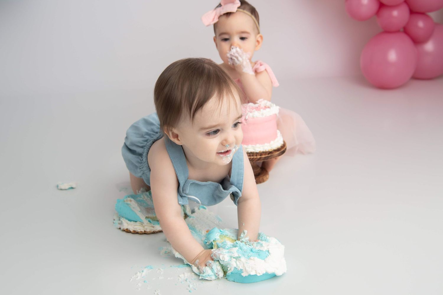 A one year old boy crawls while smashing his blue cake at a Walla Walla photography studio.