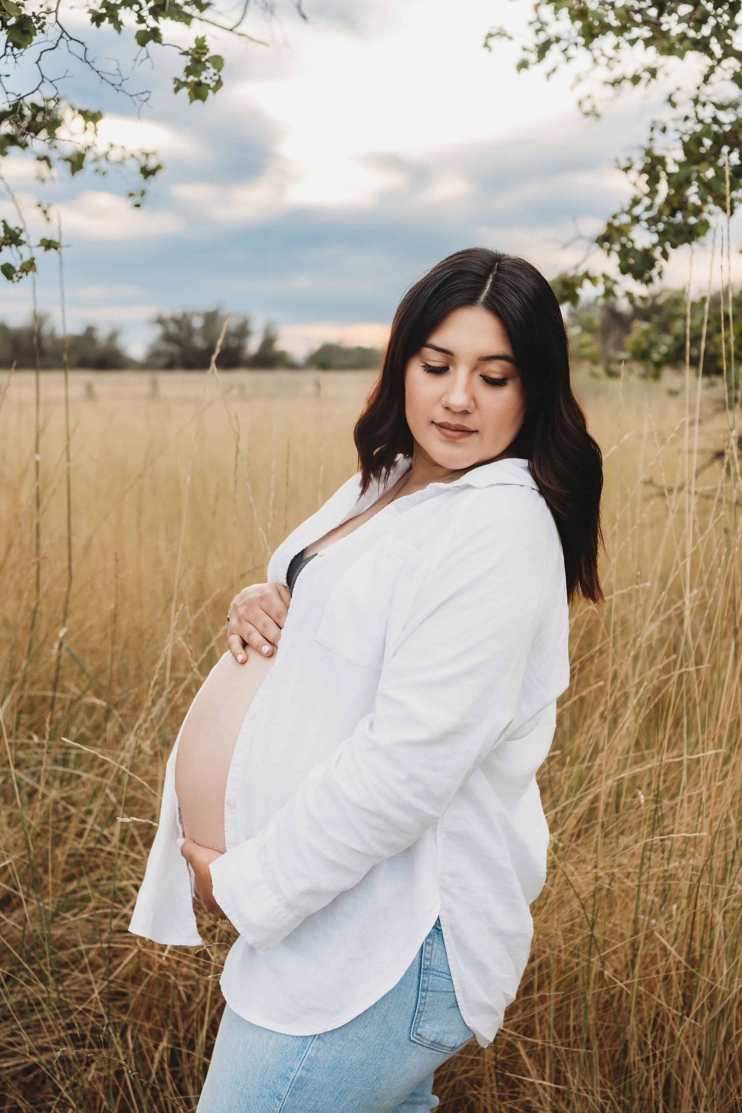 A pregnant woman looks back while holding her tummy during sunset in Walla Walla.