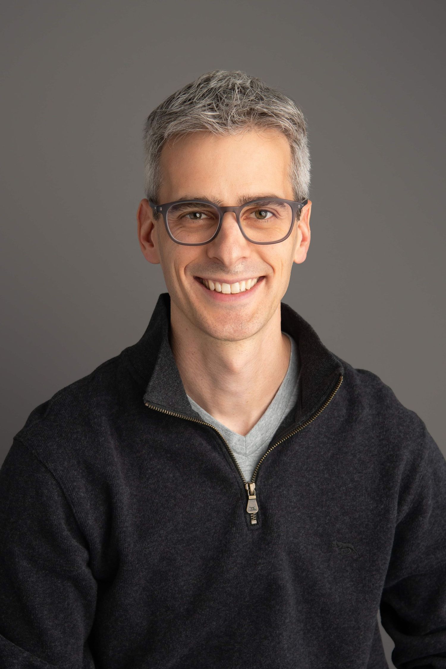 A studio portrait of a man wearing glasses and smiling confidently, photographed by a Walla Walla headshot photographer.