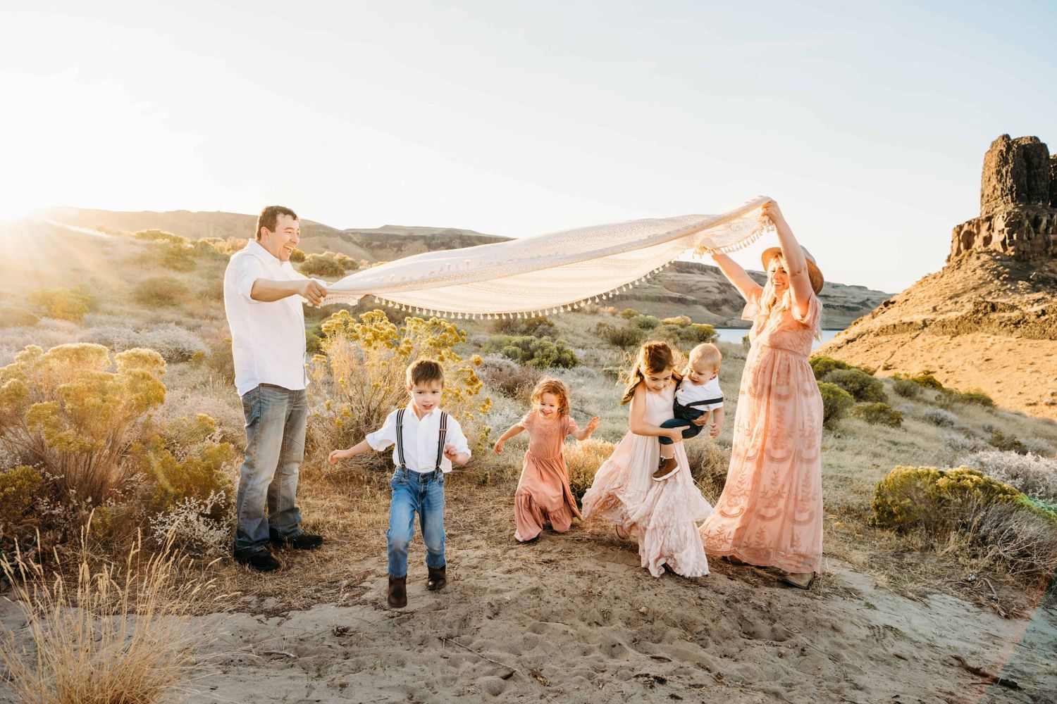 Children running playfully underneath a blanket during a family photoshoot.