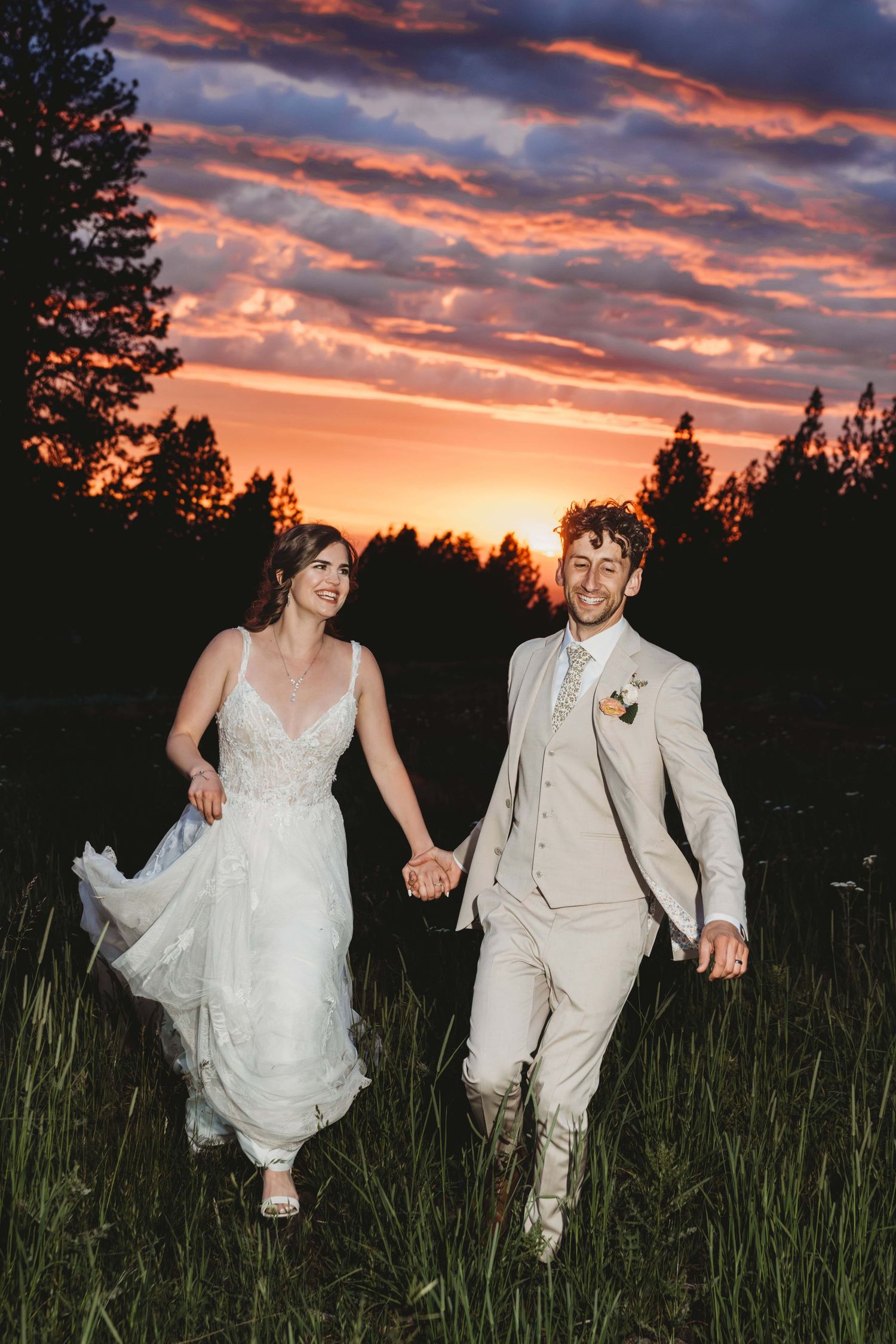 A couple running through a field during sunset after their wedding reception.