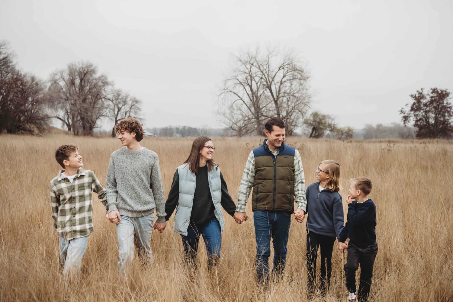 A portrait of a family with four boys walking in a field on an overcast day in Walla Walla.