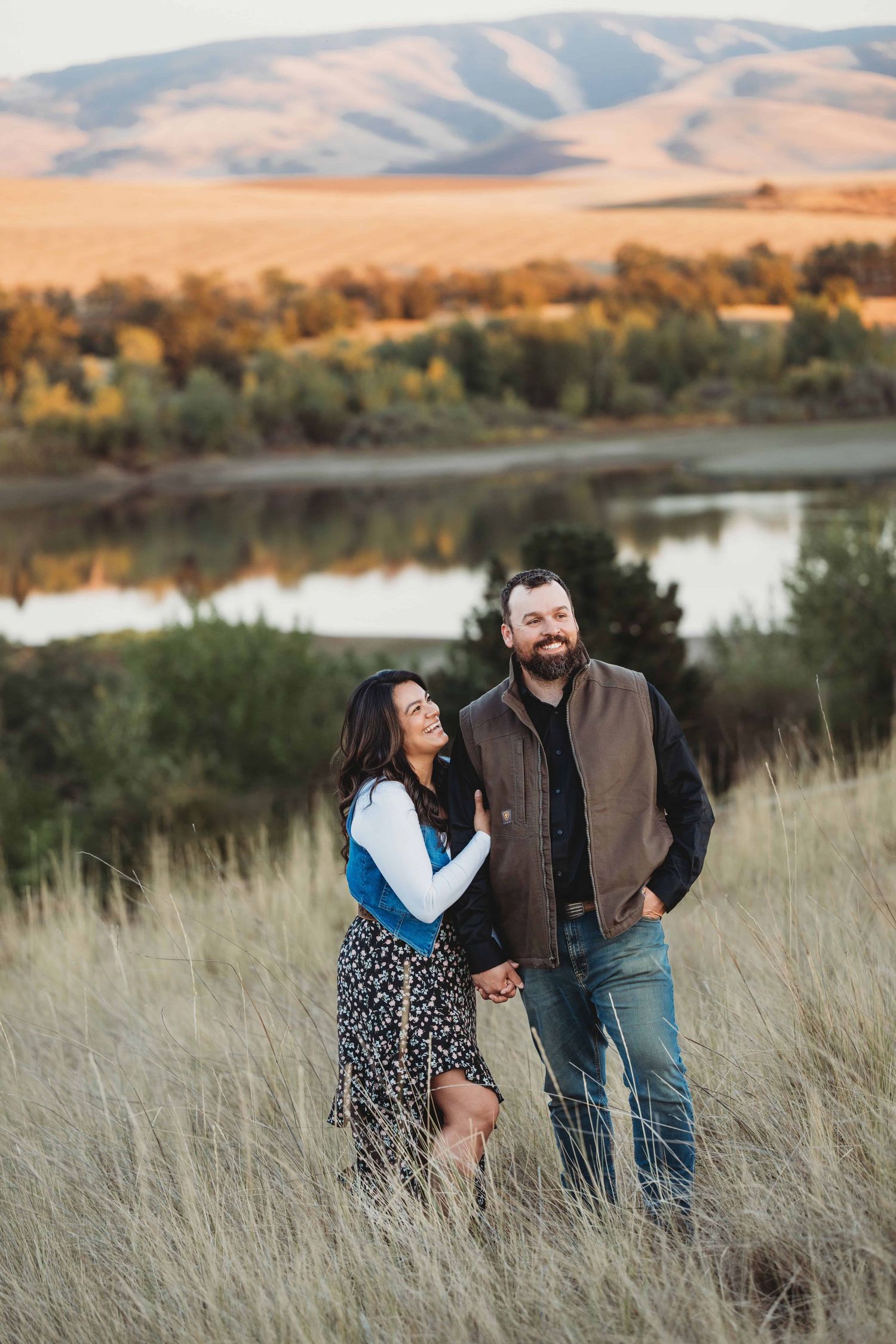 Outdoor couples photo session featuring a couple embracing with rolling hills in the background.
