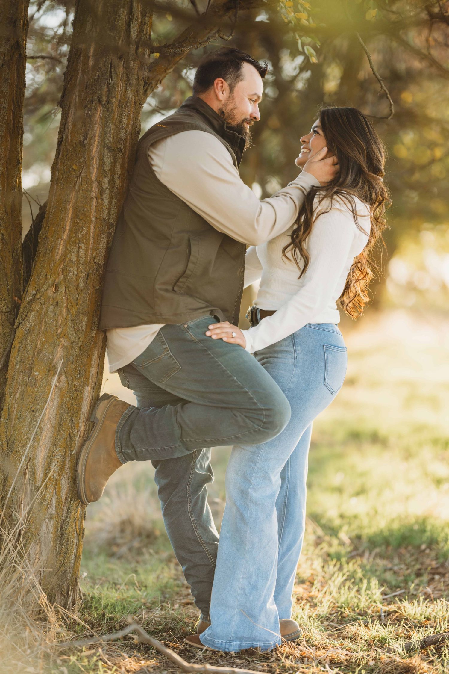 A man leaning against a tree and embracing his wife.