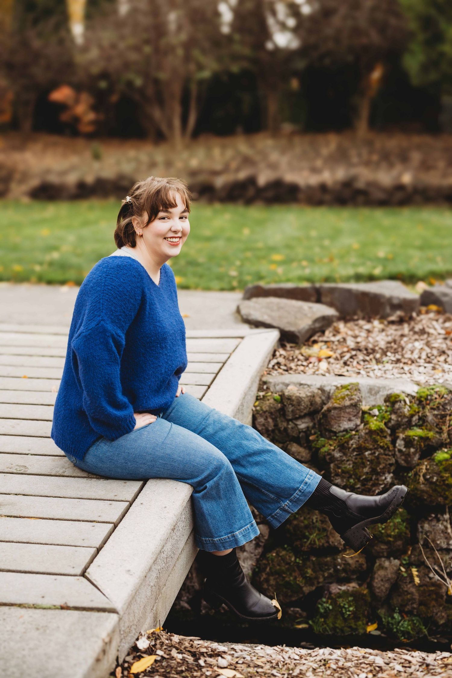 A senior sitting on a small wooden bridge at Whitman College in Walla Walla.