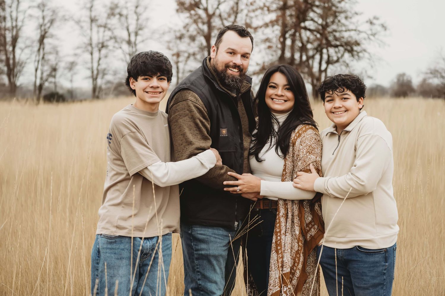 A family of four wearing neutral tones in a brown field at Whitman Mission in Walla Walla.