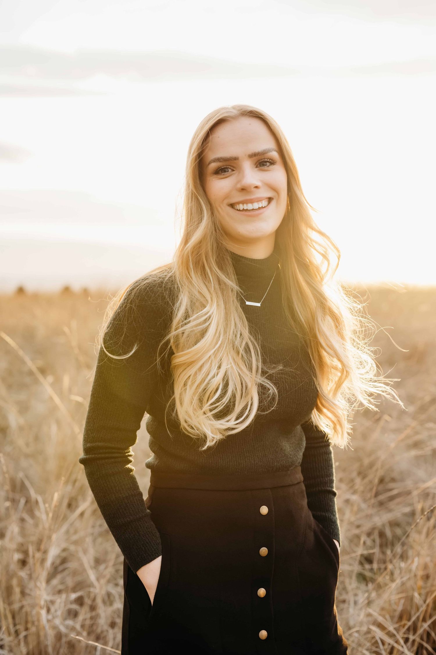 A backlit golden hour portrait of a woman looking at the camera smiling, taken by a Walla Walla photographer.
