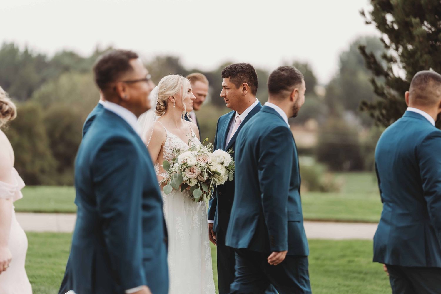A couple looking at each other with serious expressions as their wedding party walks around them.