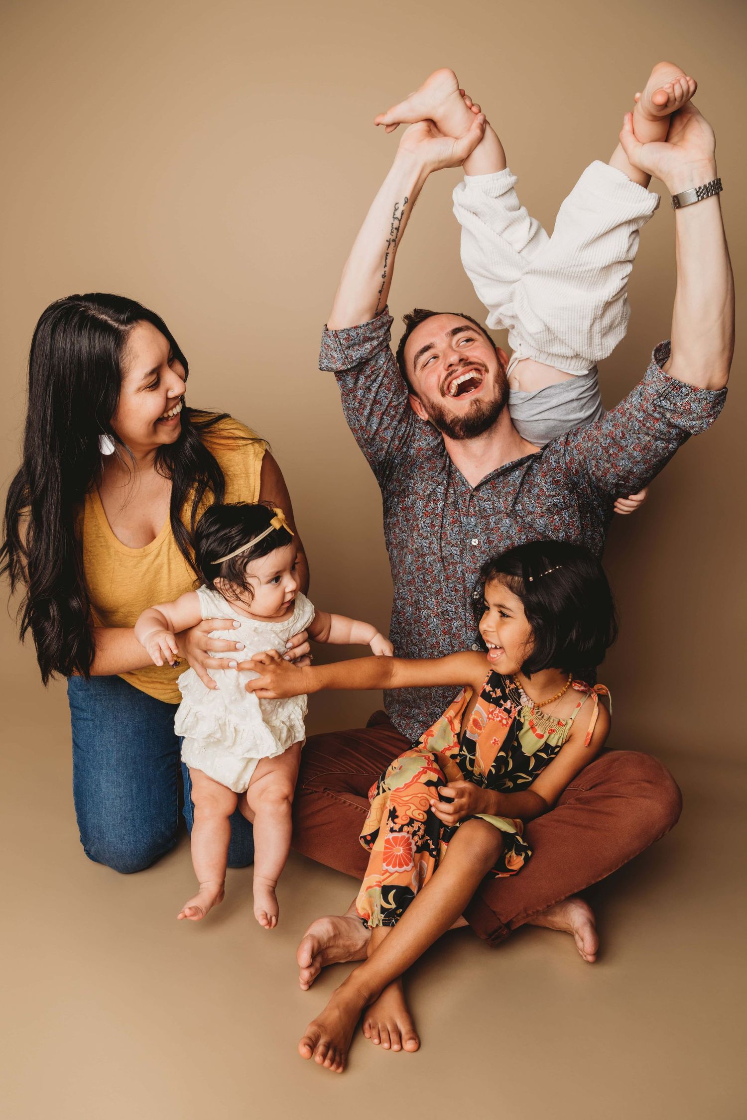 A classic candid studio portrait of a family laughing and playing together on a brown backdrop in Walla Walla.