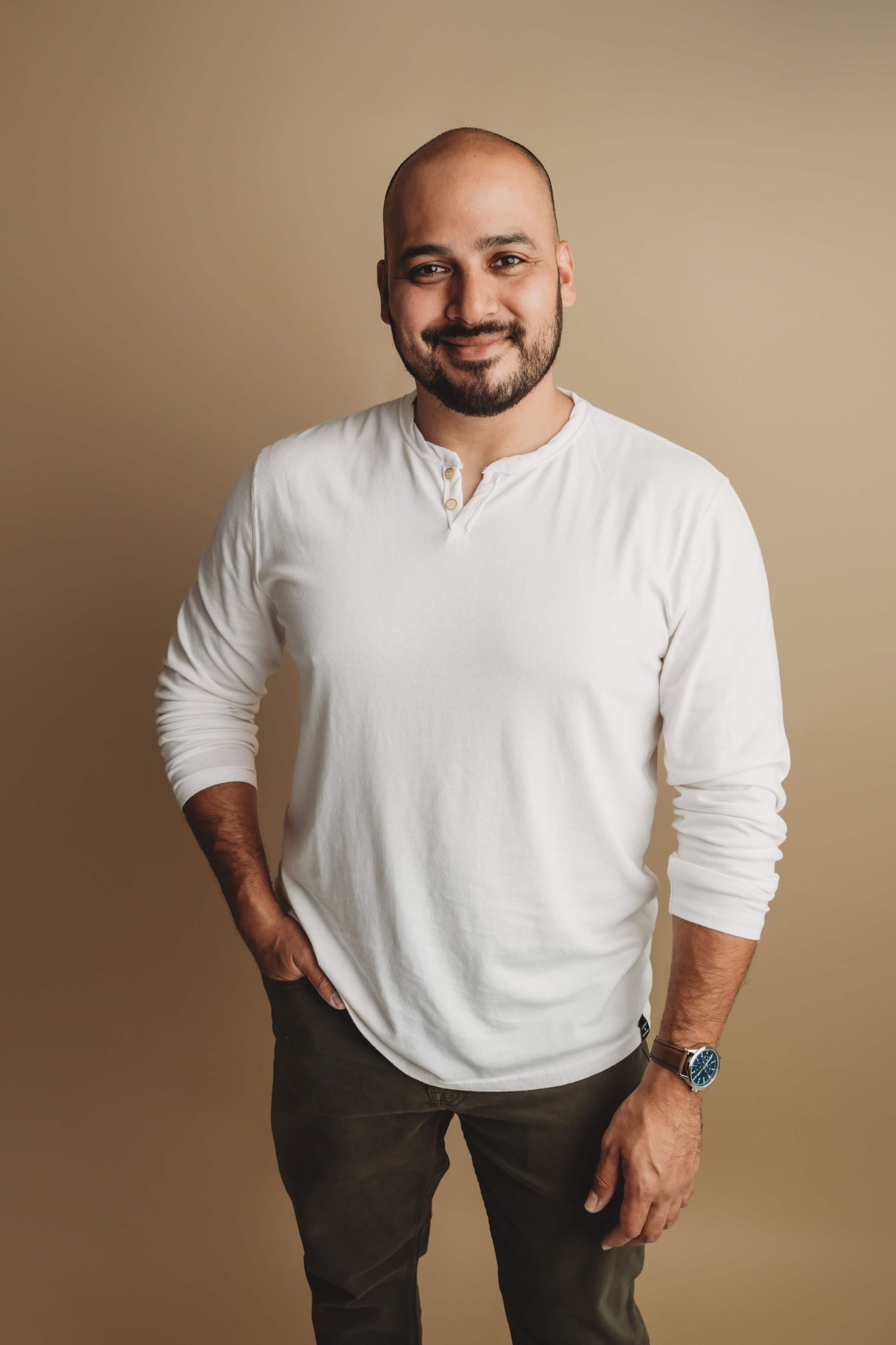 A man in a white shirt standing in front of a brown backdrop for a professional headshot image in a Walla Walla portrait studio.