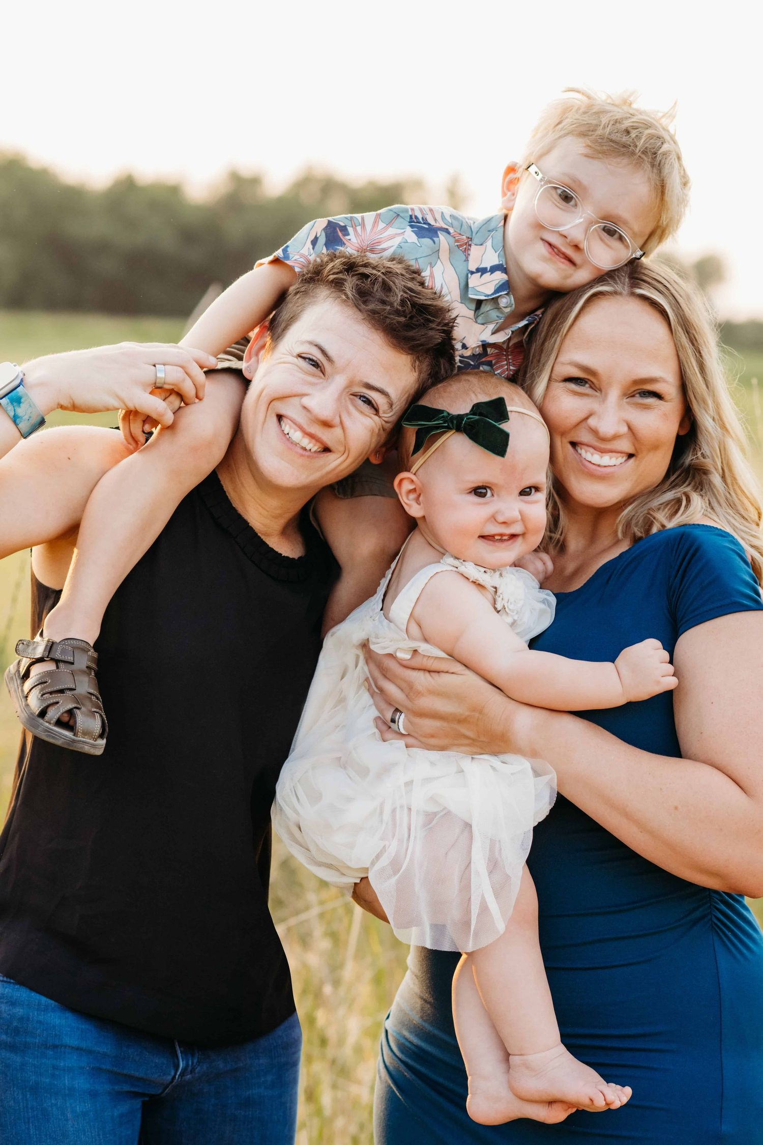 A family portrait with the parents holding two children and everyone is smiling at the camera.