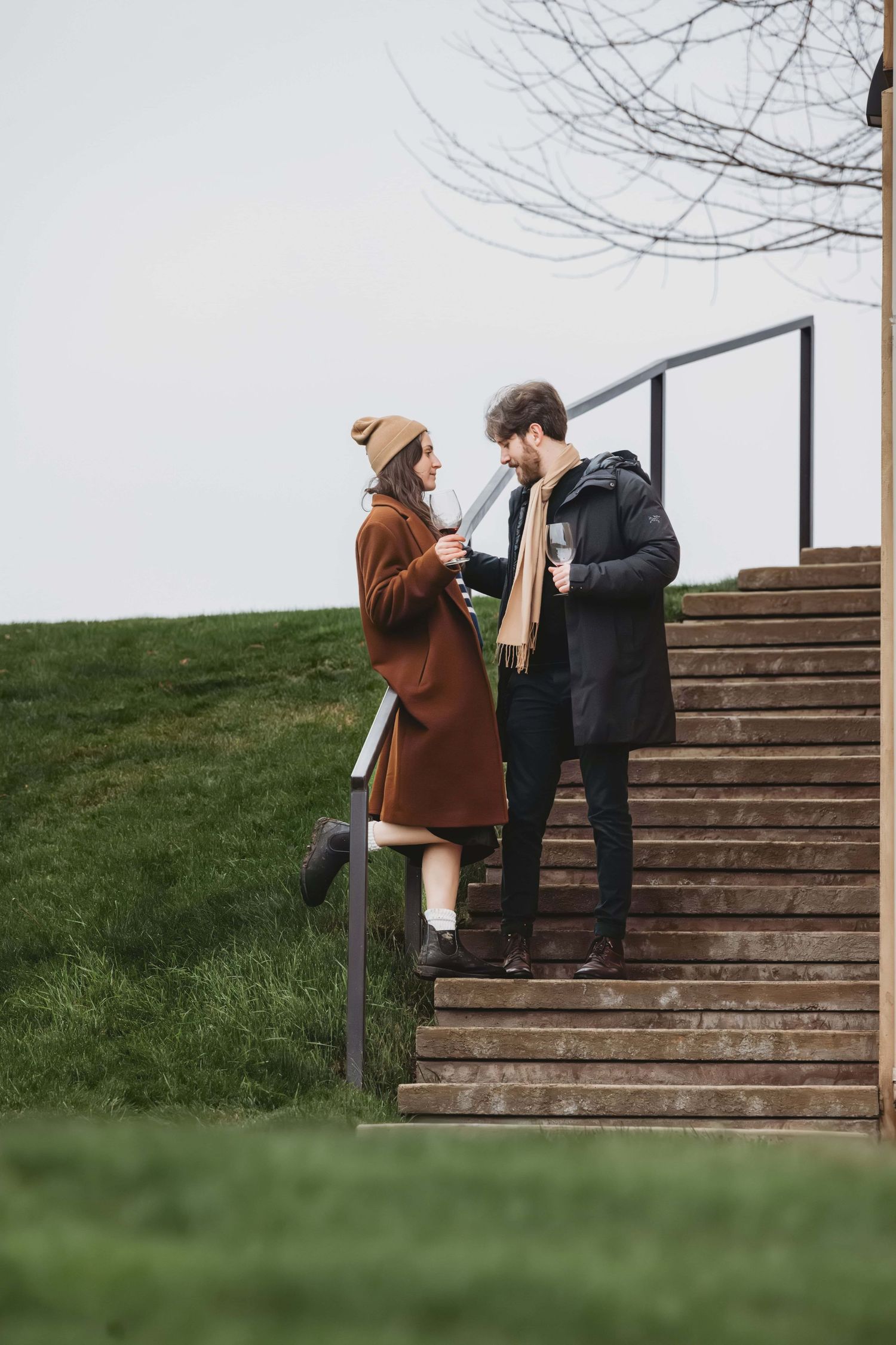 A couple standing on stairs at a winery on a cool winter day.