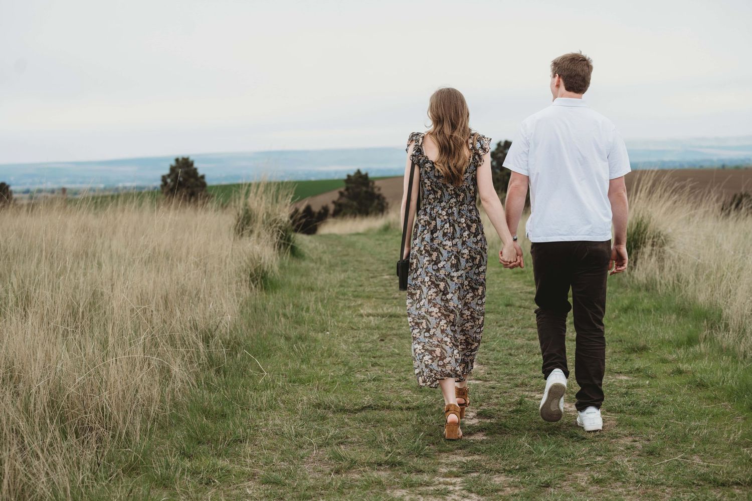 A couple walking away from the camera downhill, just after getting engaged in Walla Walla.