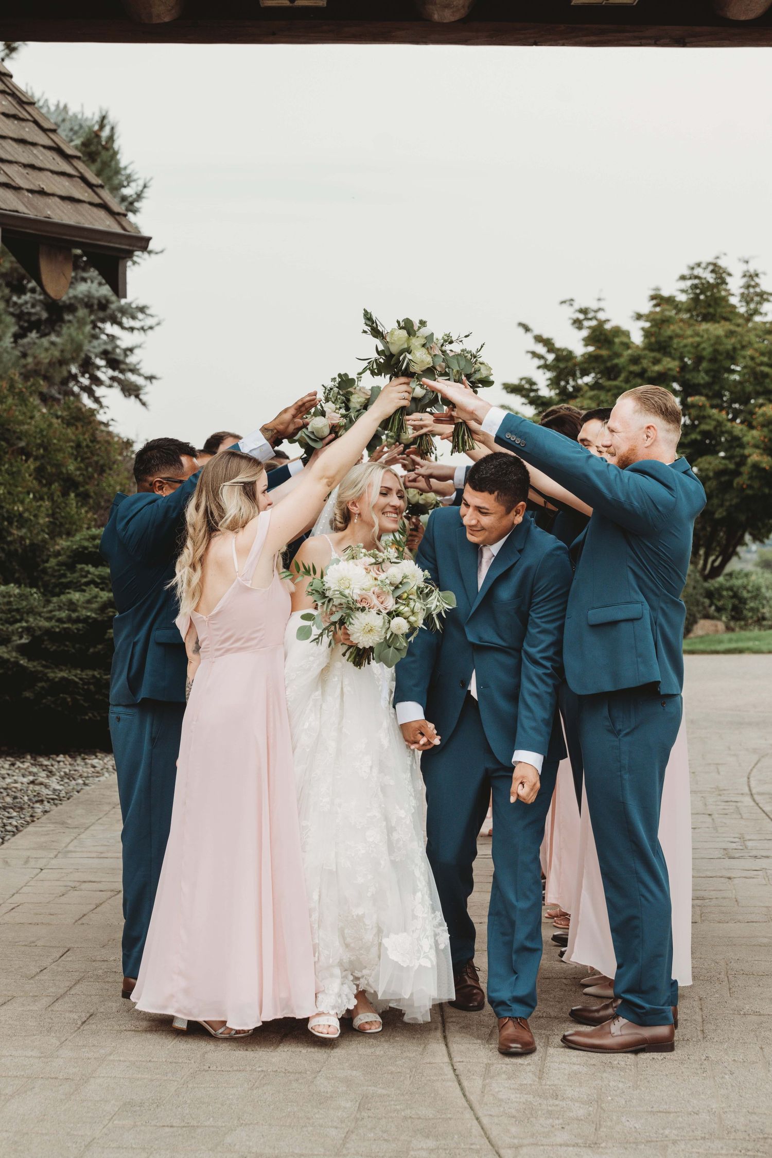 A bride and groom running through their bridal party as they hold their hands up to create a tunnel.