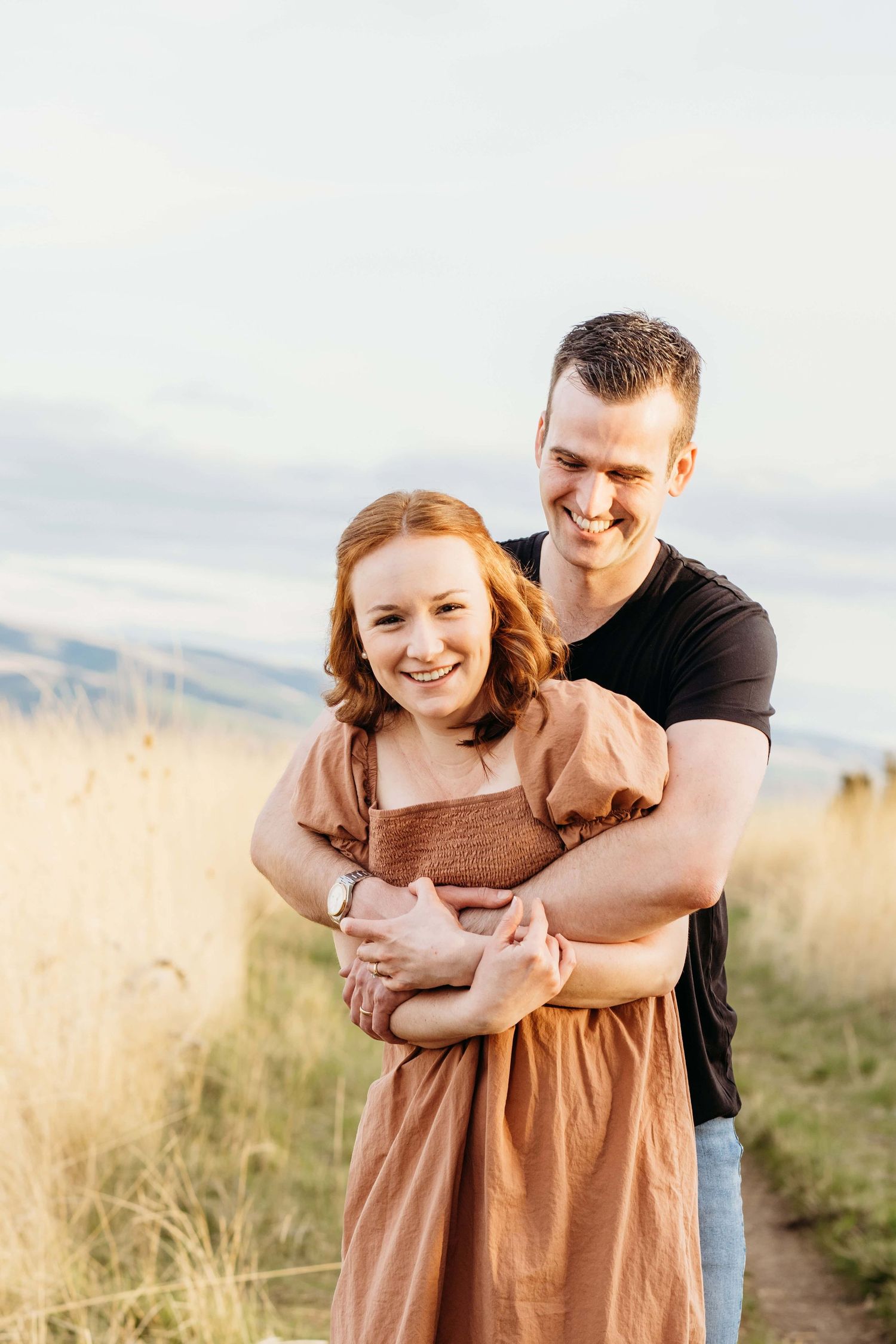 Couple laughing together on a hillside trail during an outdoor couples photography session near Walla Walla.