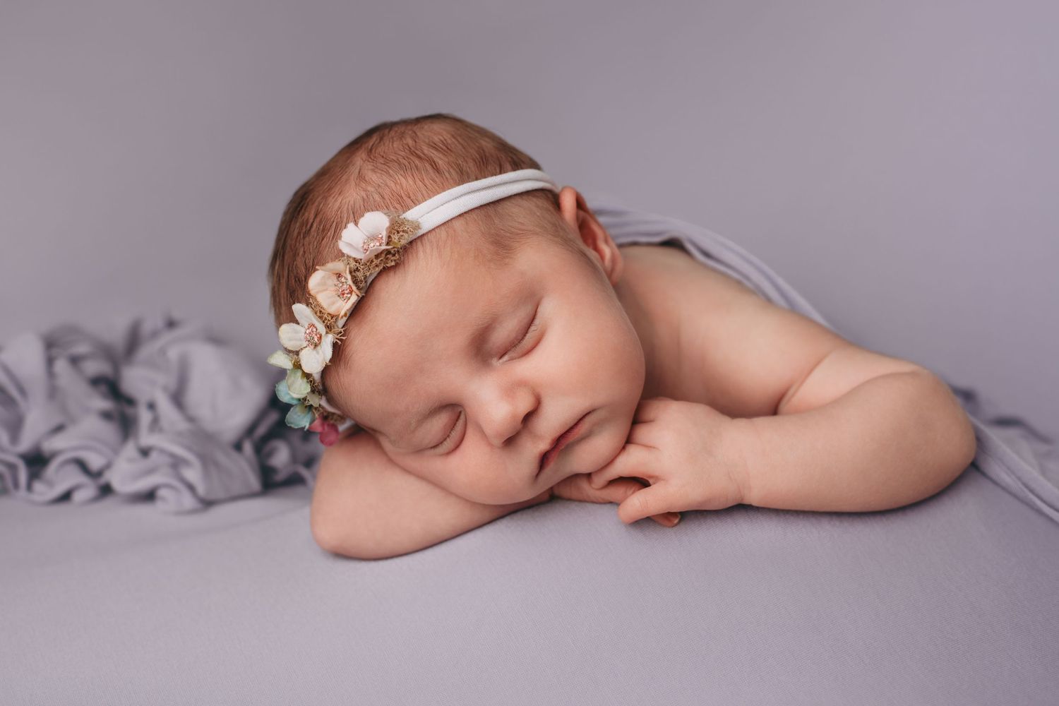 Studio newborn portrait by a Walla Walla photographer showing a sleeping baby resting on folded arms.