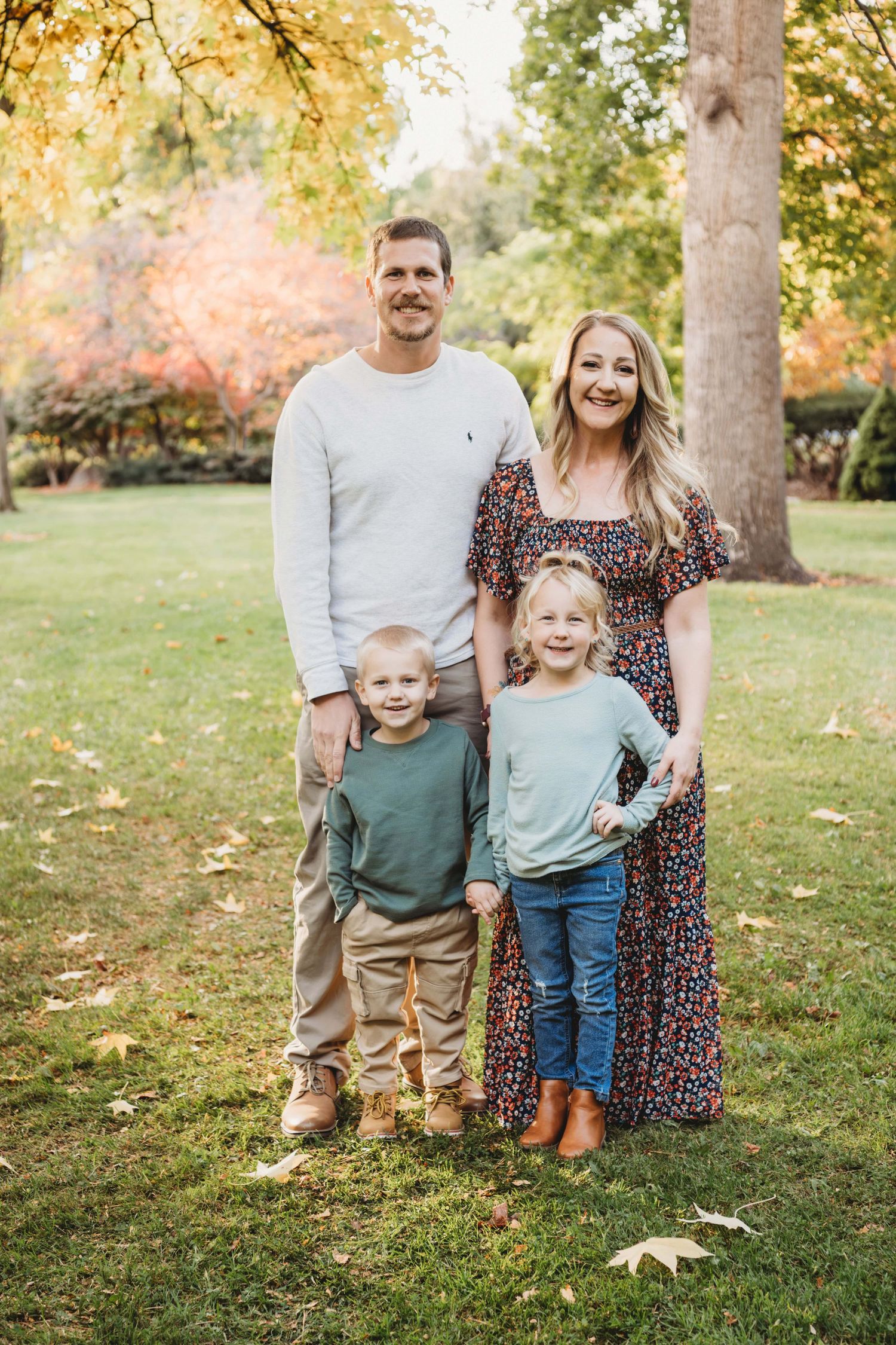 Fall family portrait by a Walla Walla photographer showing parents and young children standing together in a park.