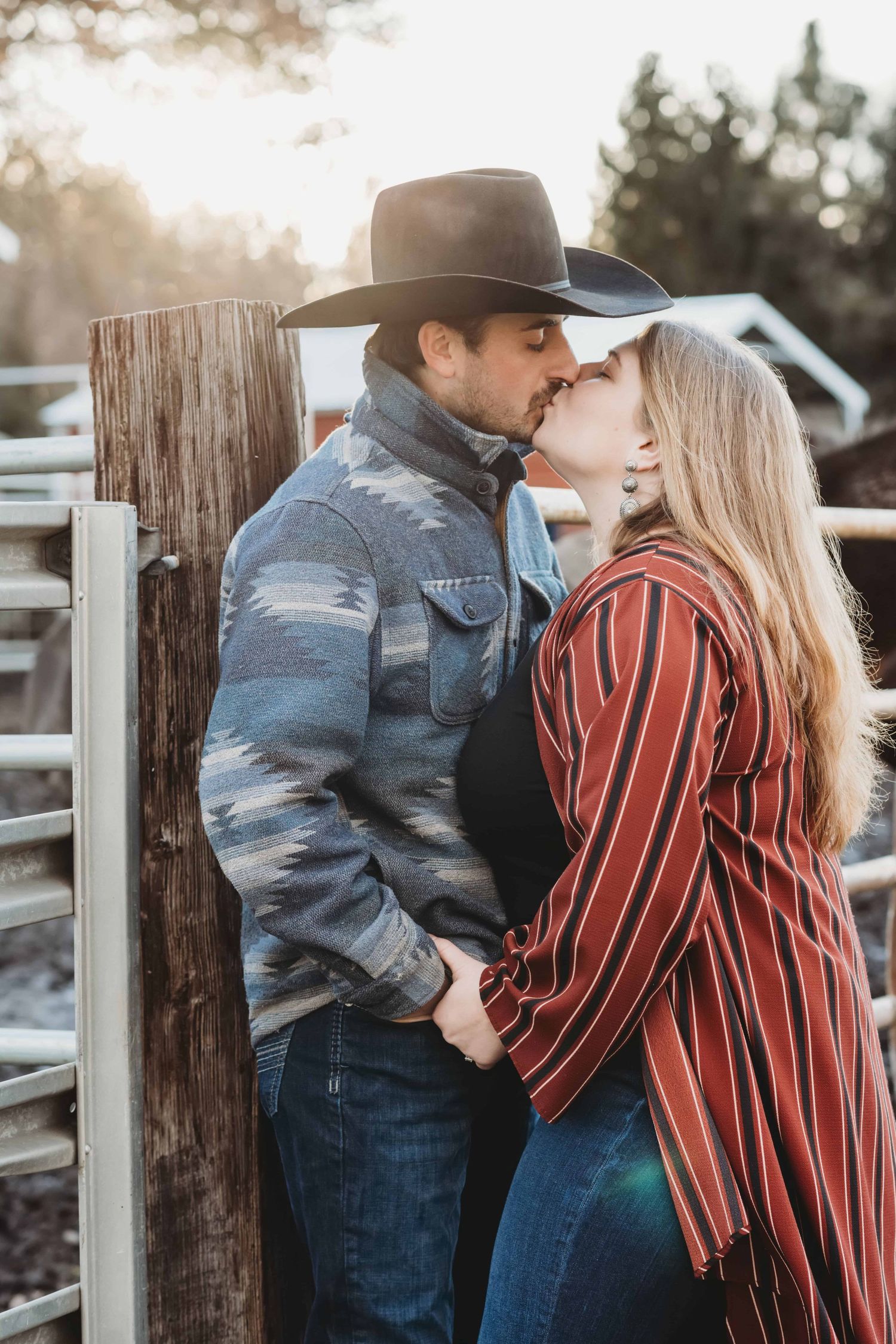 Couple kissing near a rustic fence during an outdoor couples session in Walla Walla, Washington.