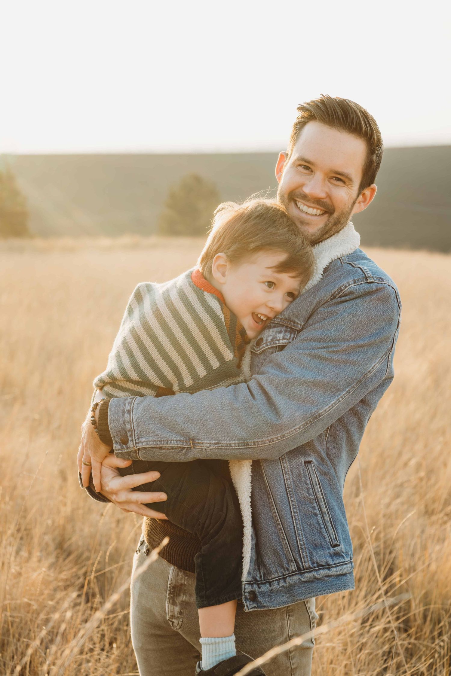 A Walla Walla photographer captures a candid moment of a dad with his son laughing in a field.