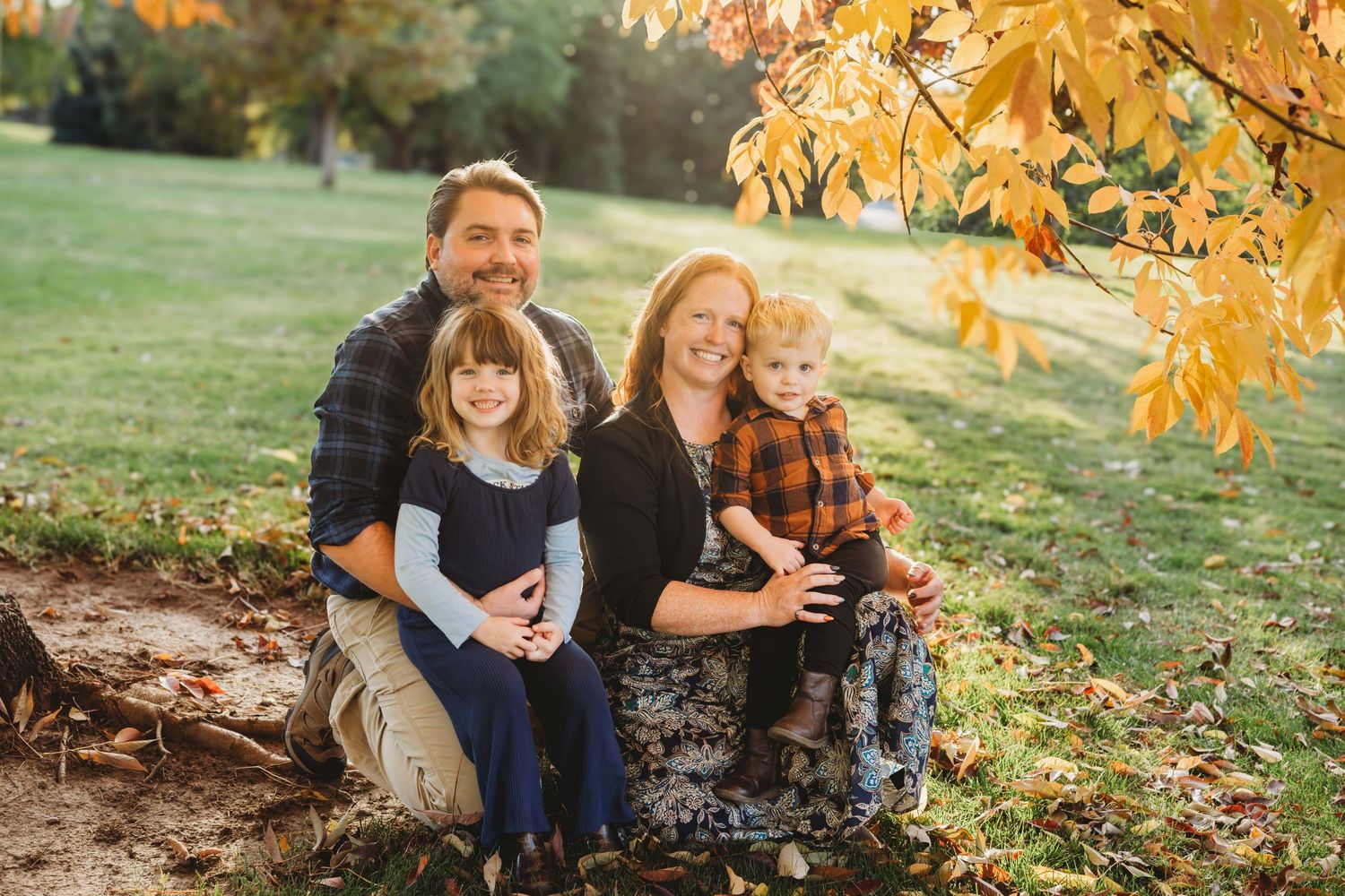 Walla Walla family photography session showing parents and young children sitting together in a park during fall.