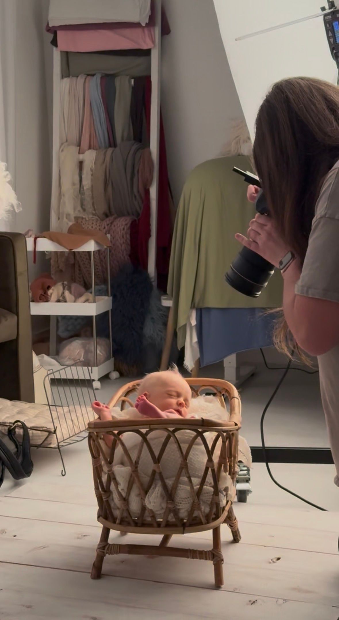 A behind the scenes photo of Brittani Smith Photography photographing a newborn that is sleeping in a bassinet.