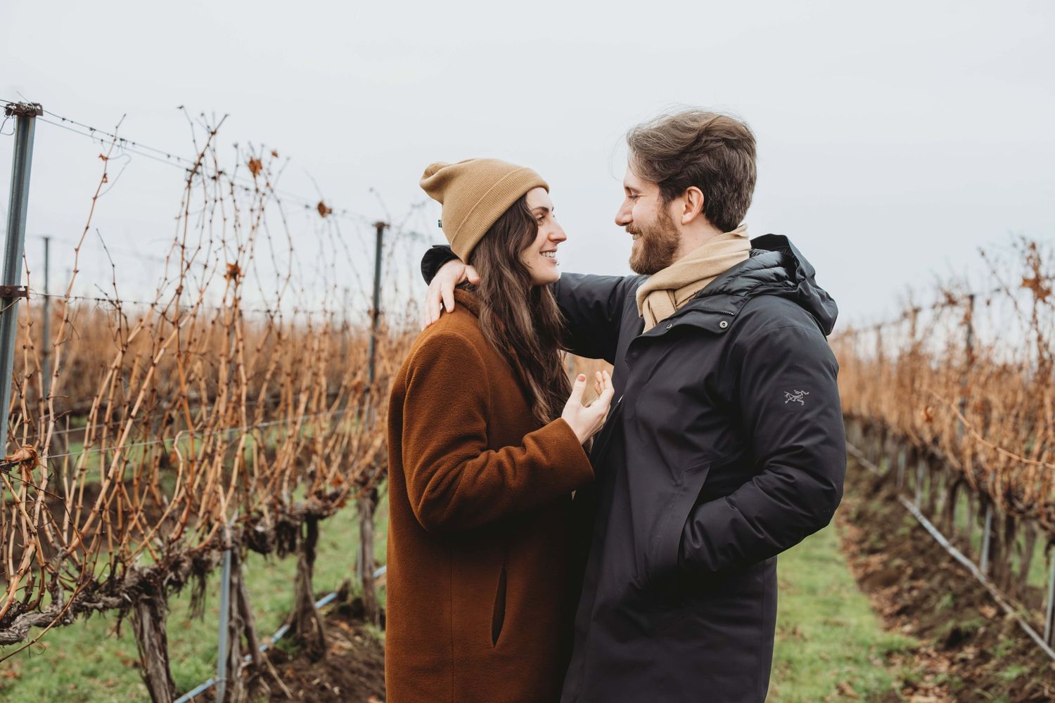 A couple looking at each other smiling in a vineyard in the winter in Walla Walla.