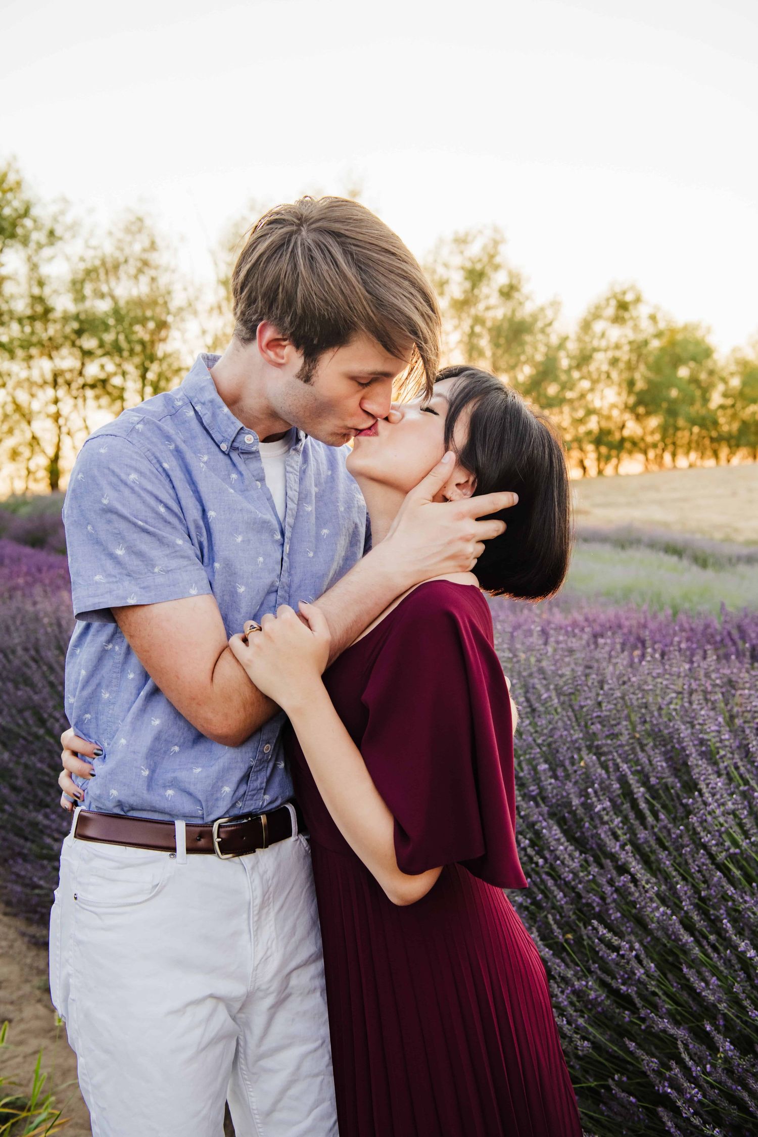 A couple kissing wearing colorful clothing in a lavender field.