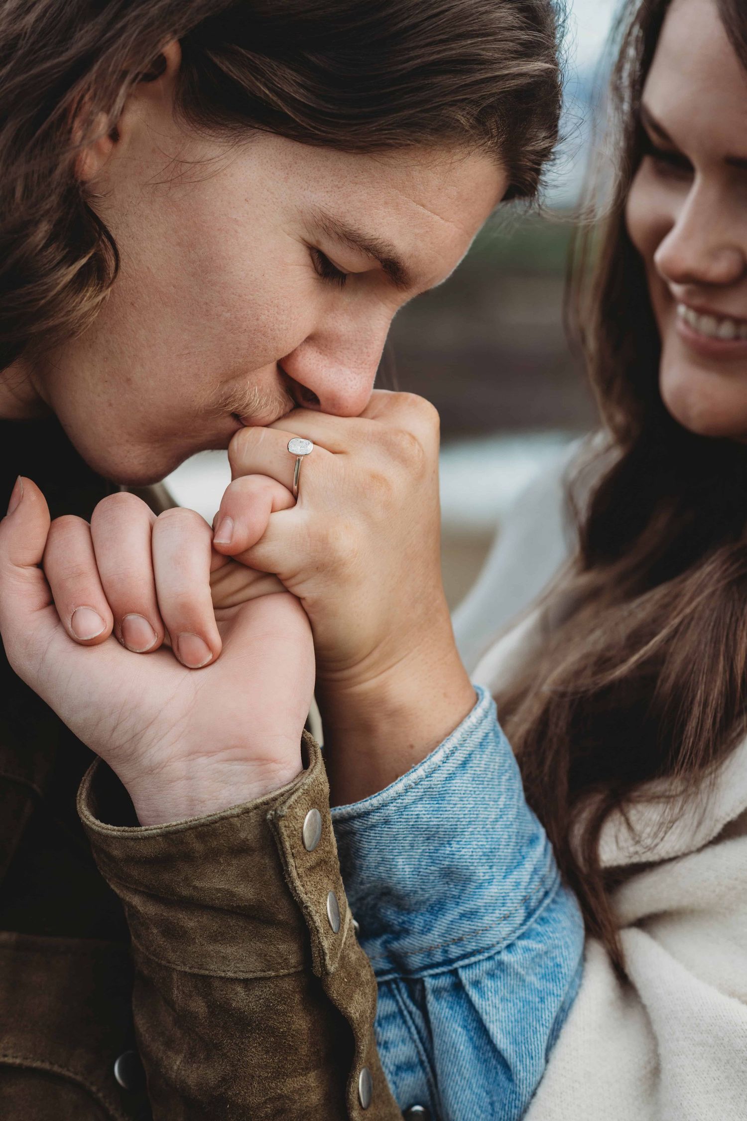 A close up of a man giving his fiancé a pinky promise right after proposing to her.