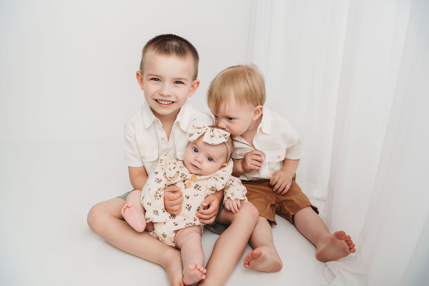 Two boys hugging and kissing their baby sister in a timeless portrait taken by a Walla Walla photographer.