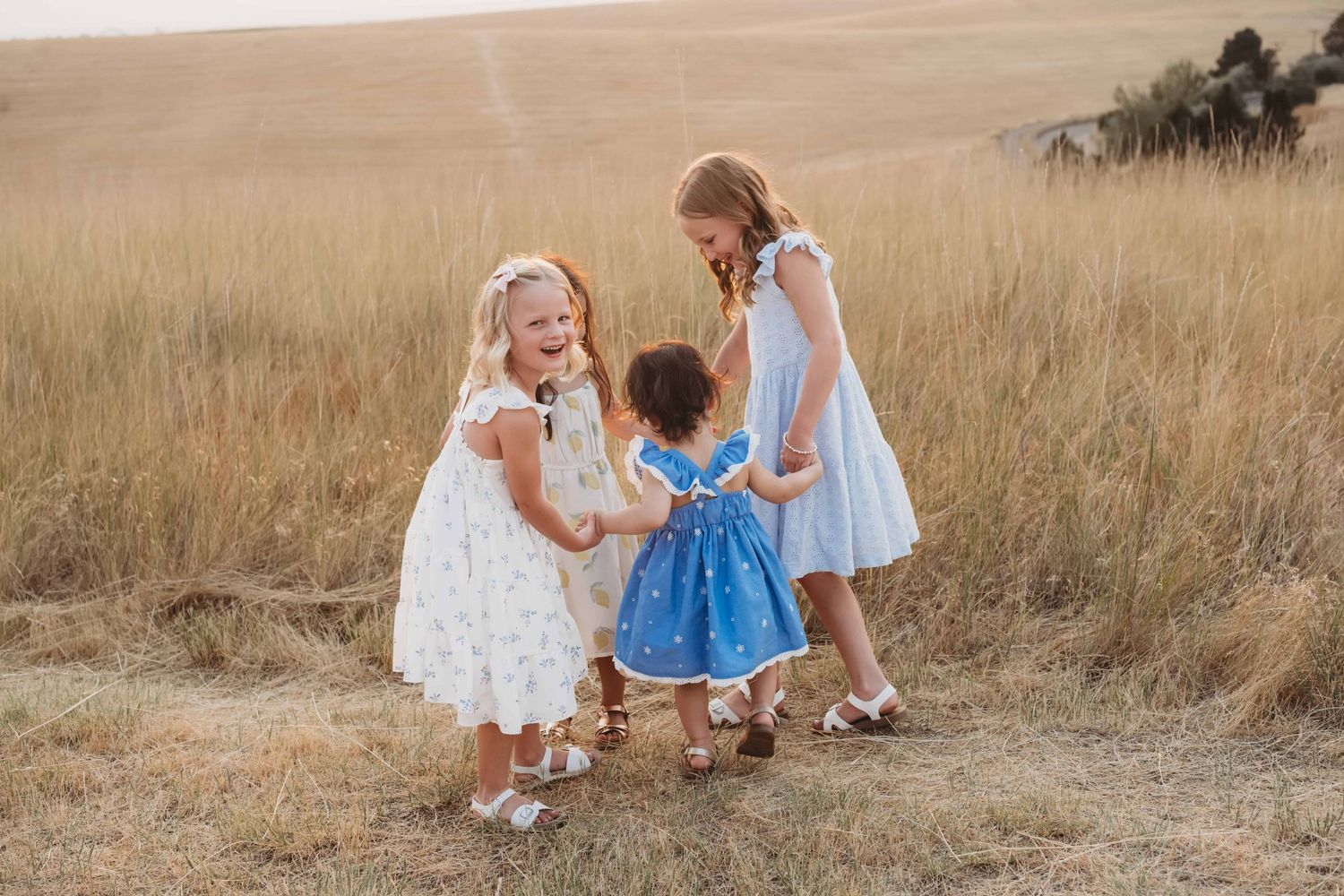 A child photographer captures four girls holding hands and spinning in a circle at Bennington Lake in Walla Walla.