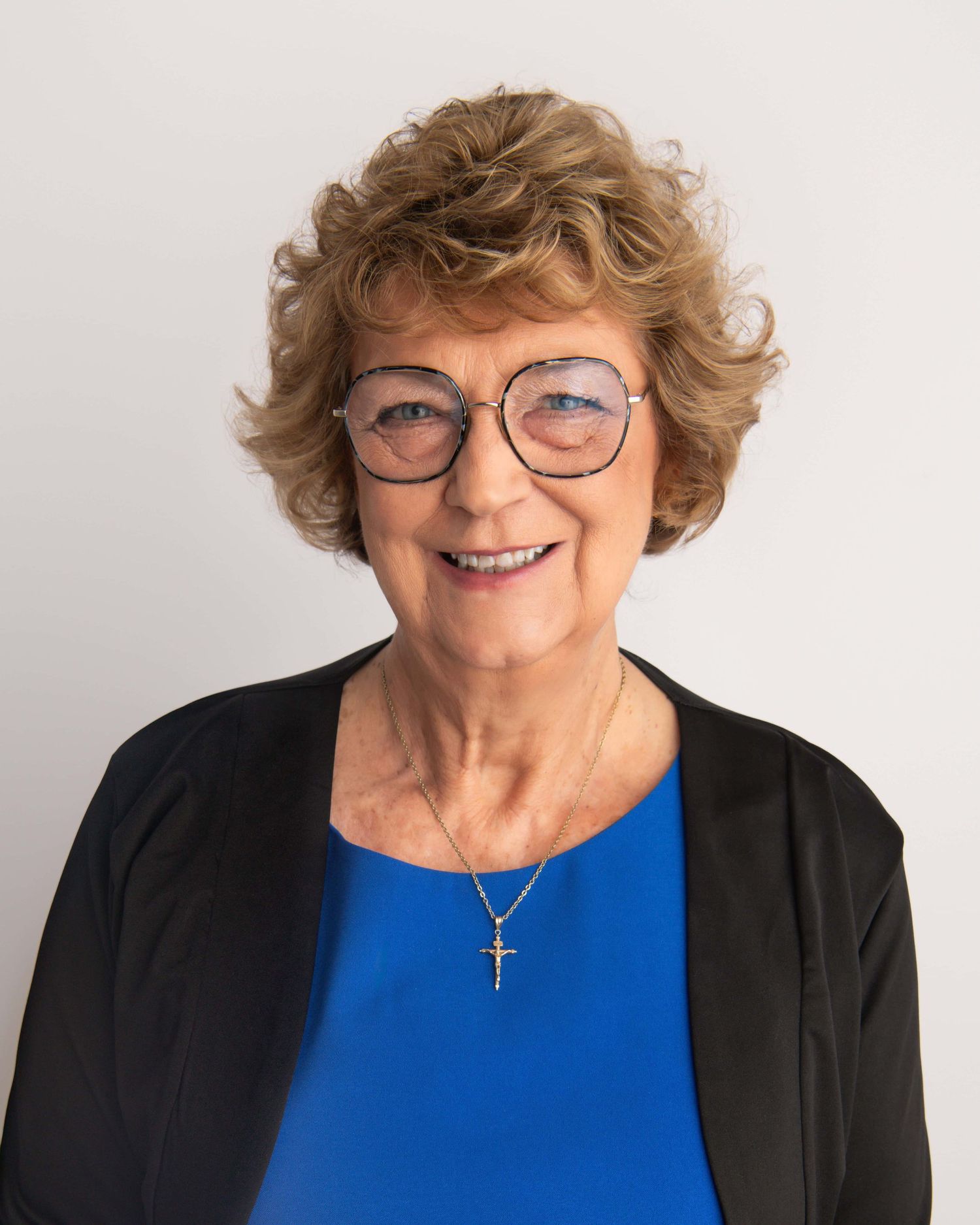 Headshot portrait of a woman wearing a blue shirt and blazer in front of a white backdrop.