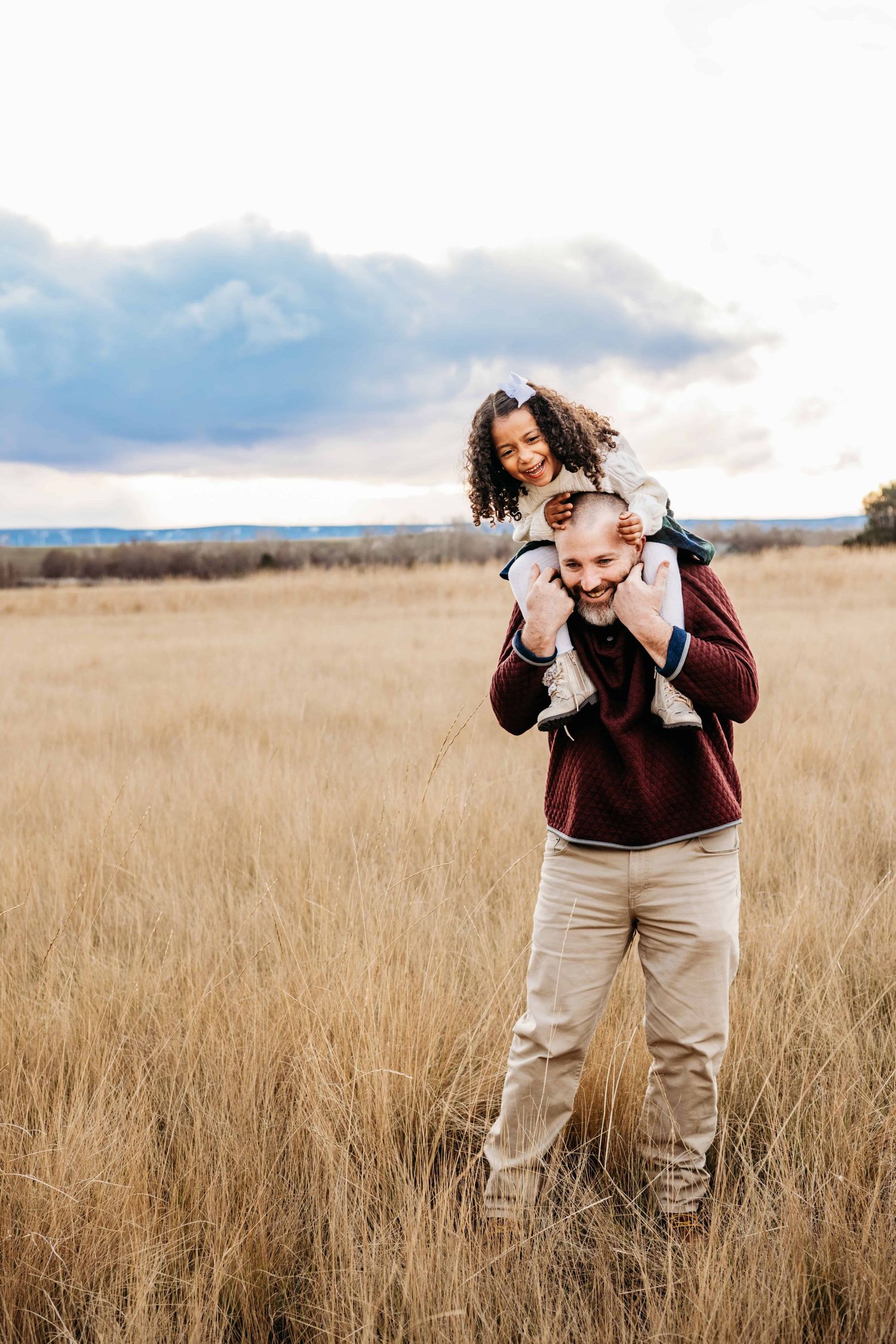 A Walla Walla photographer captures a candid moment of a granddaughter on her grandfather's shoulders during sunset.