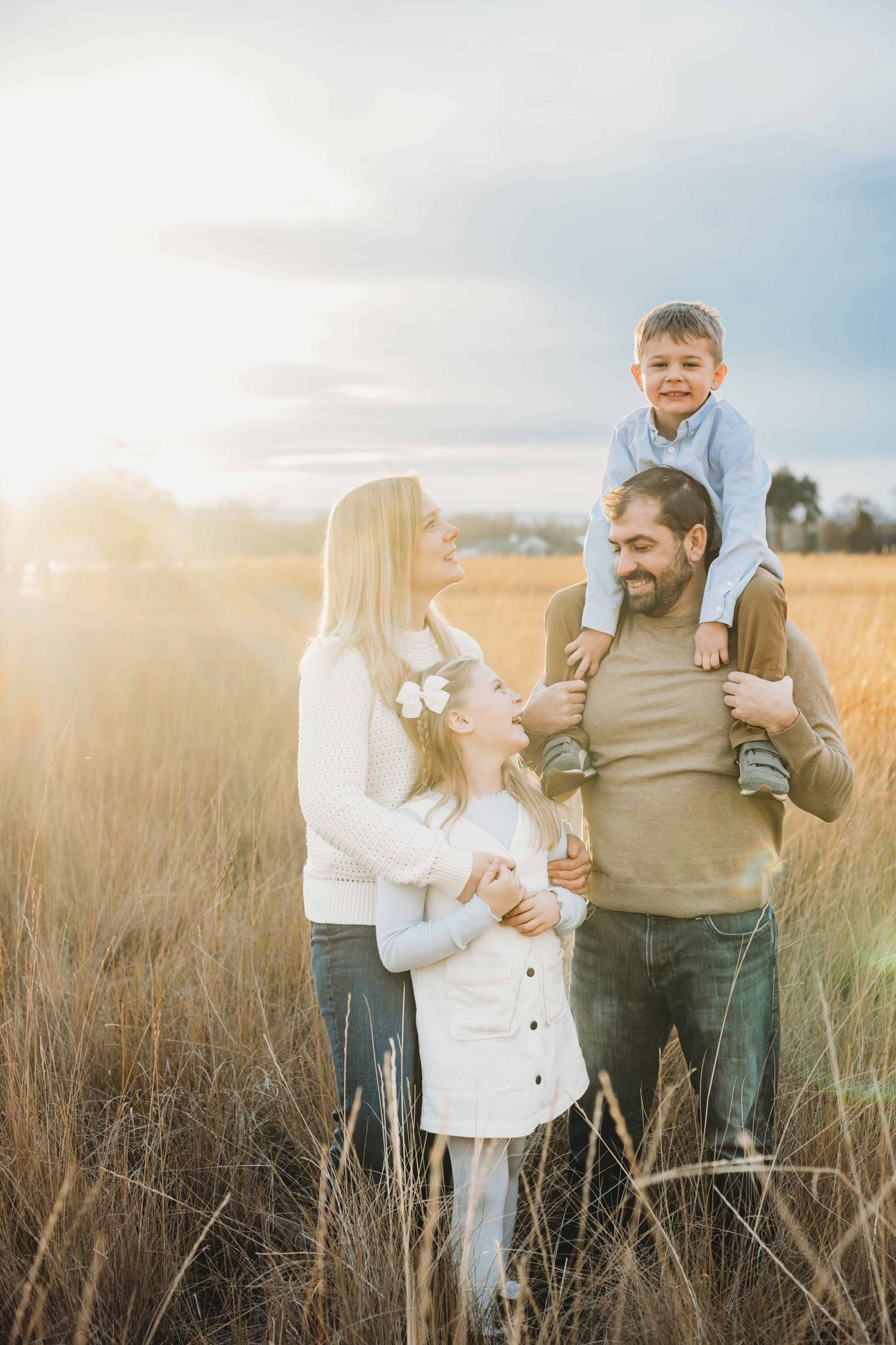 A photographer captures a family of four with a little boy on his dad's shoulders and beautiful golden lighting in Walla Walla.