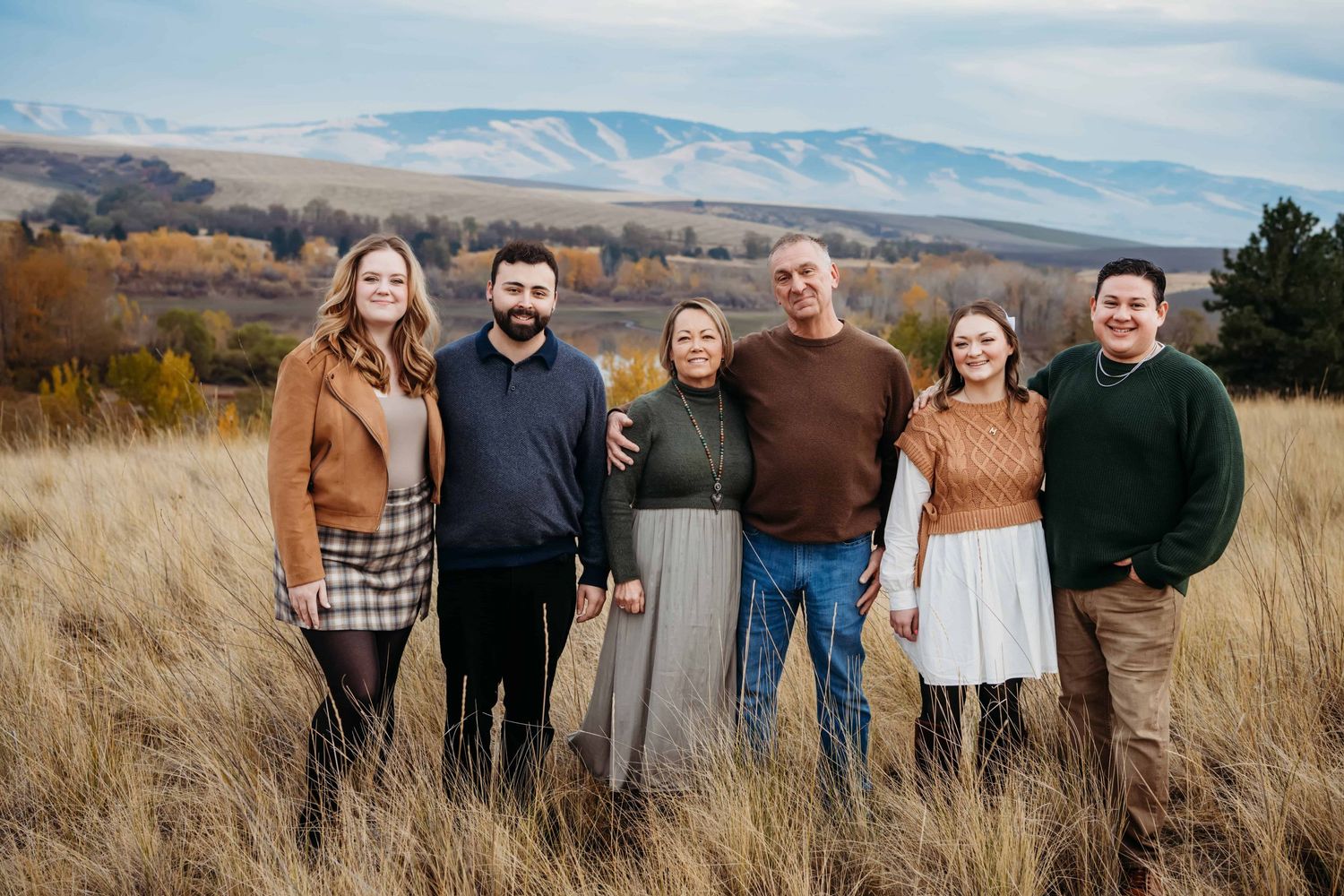 A portrait of a family wearing fall colors in a field with Bennington Lake and mountains in the background in Walla Walla.